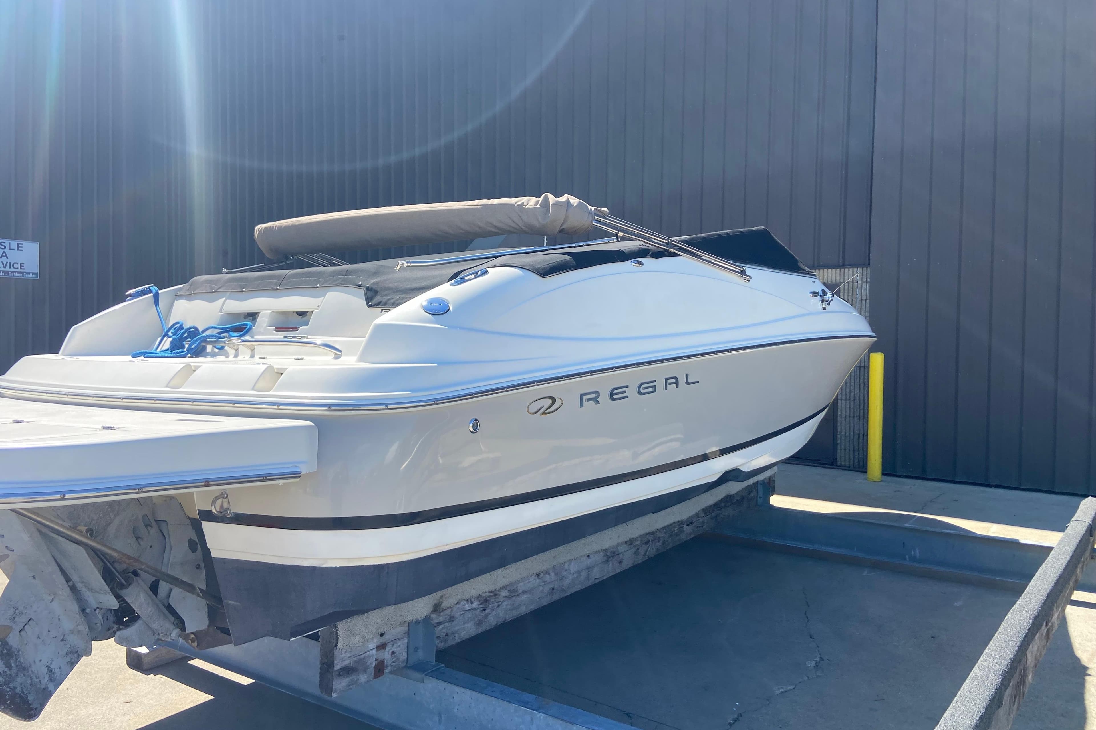 2005 Regal 2400 Bowrider boat on trailer, parked outdoors in sunlight.