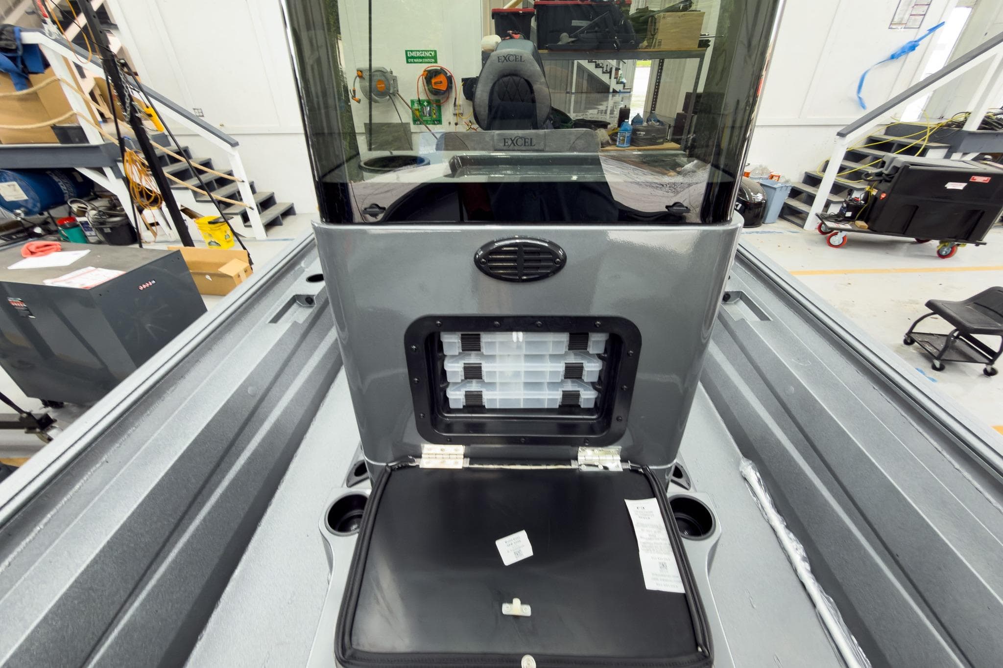2026 Excel 230 Bay Pro Elite boat interior with storage compartment open in a workshop.