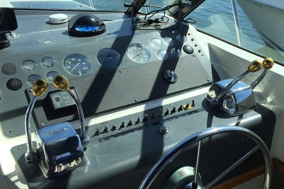 Helm of 1989 Tiara Yachts 3100 Open with steering wheel and control levers.