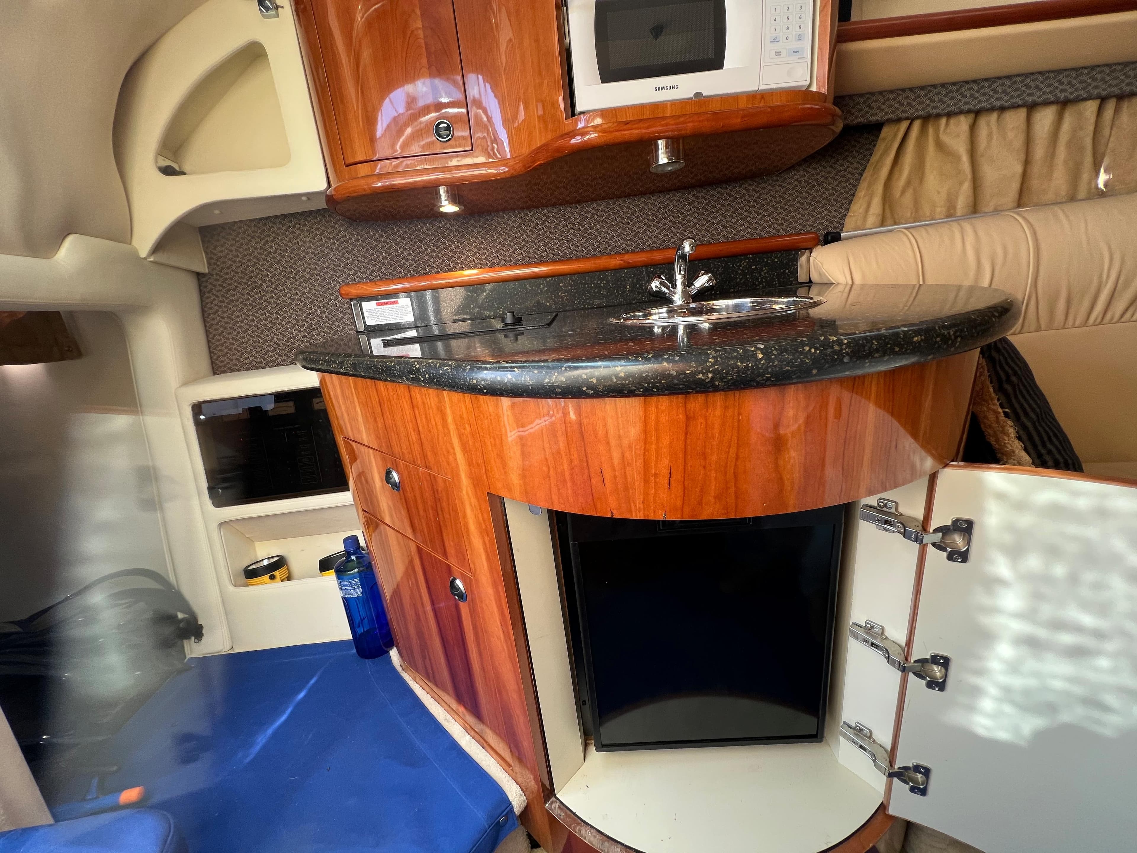 2004 Cobalt 360 boat interior with kitchenette, microwave, sink, and storage cabinets.