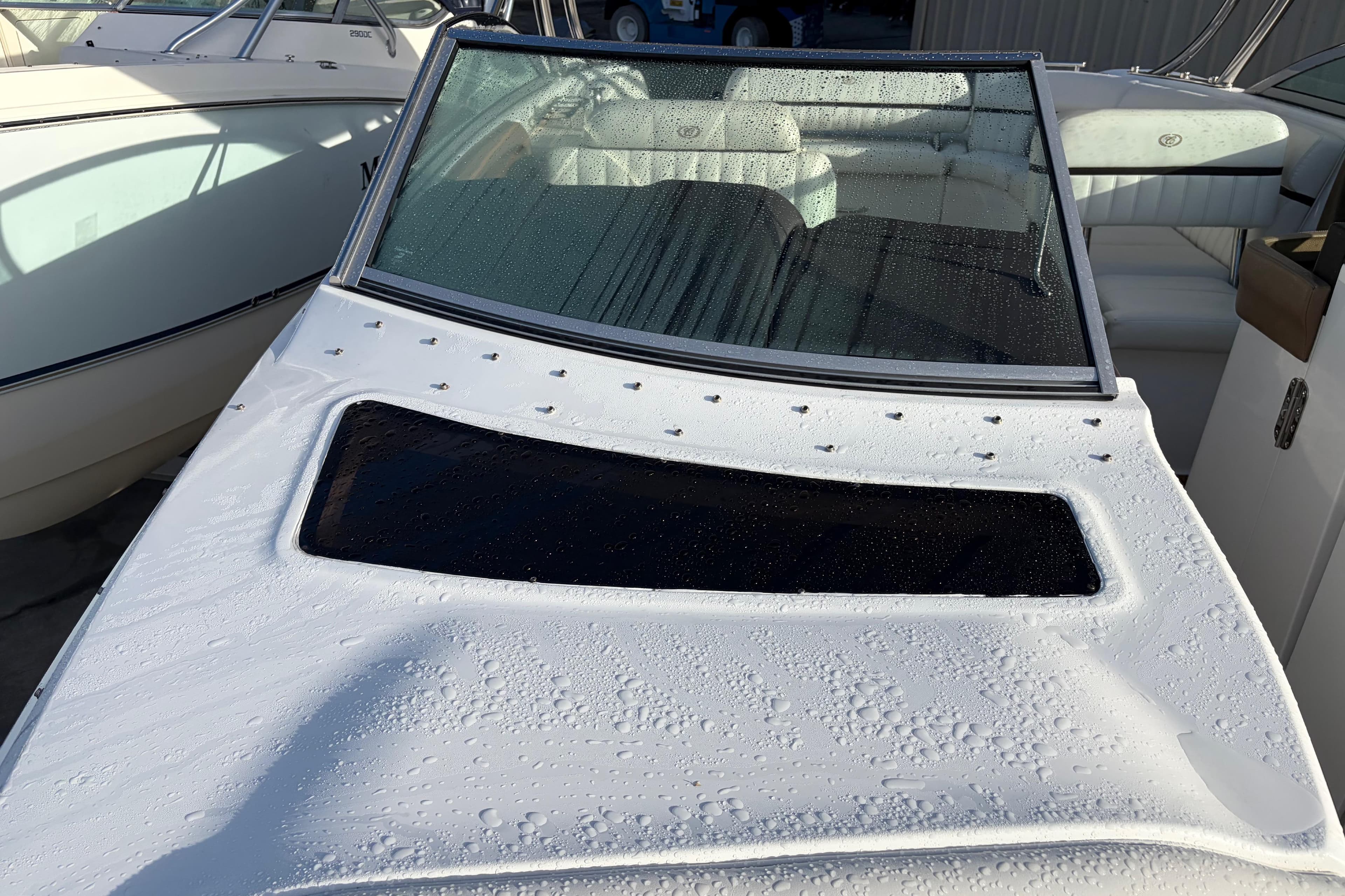 2015 Cobalt 336 boat with wet deck and windshield, parked beside another vessel.