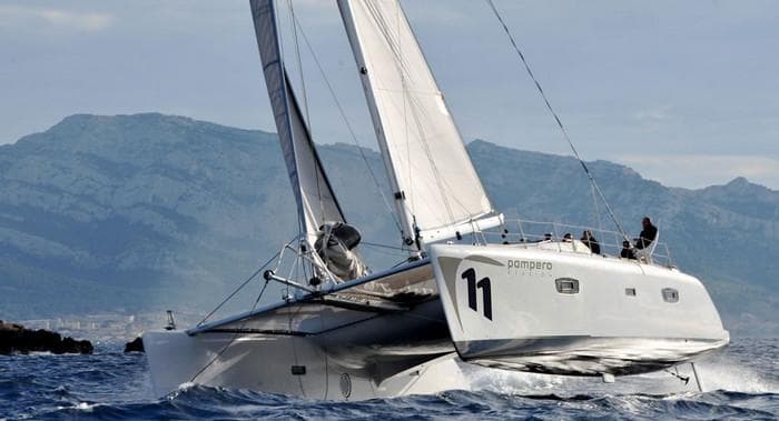 2011 Catamaran TS 52.8 sailing on open water with mountainous backdrop.