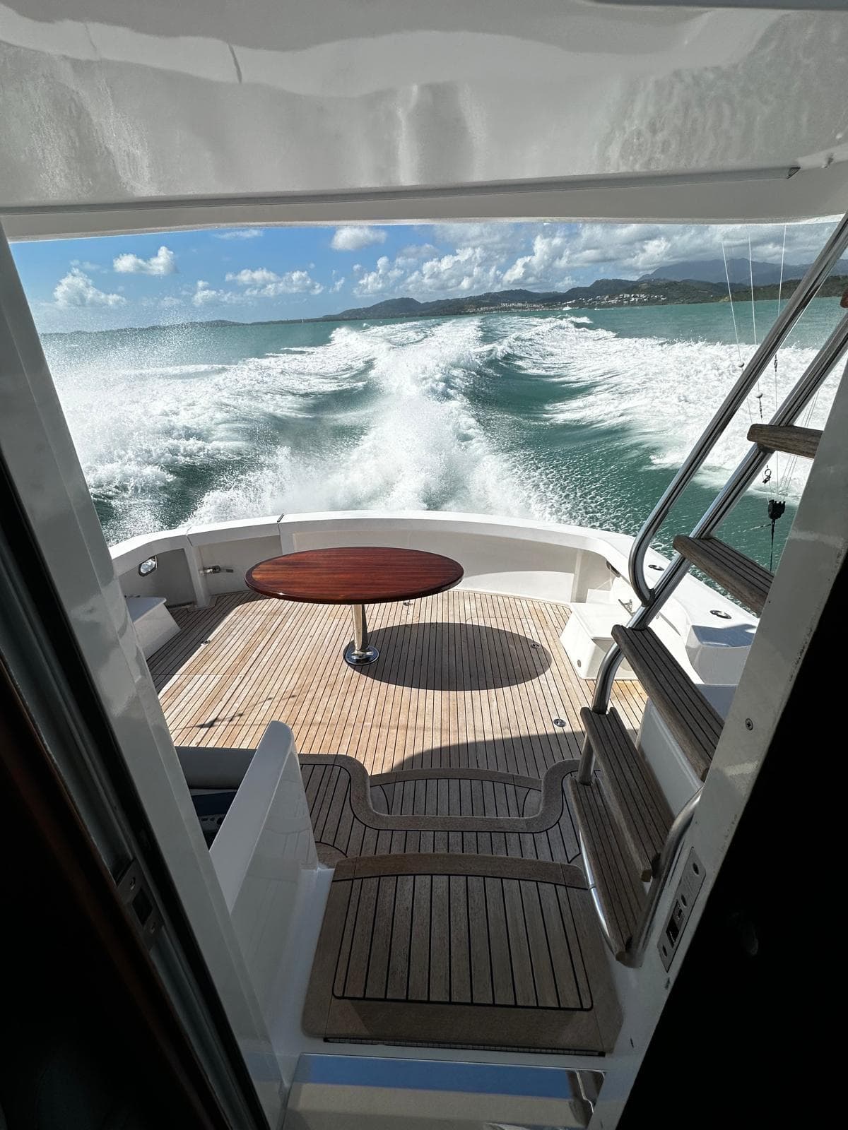 2011 Hatteras GT60 yacht cruising, view from deck with ocean waves and clear sky.