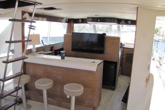 Interior of 1973 Chris-Craft 55 Commander yacht with bar, stools, and mounted TV.