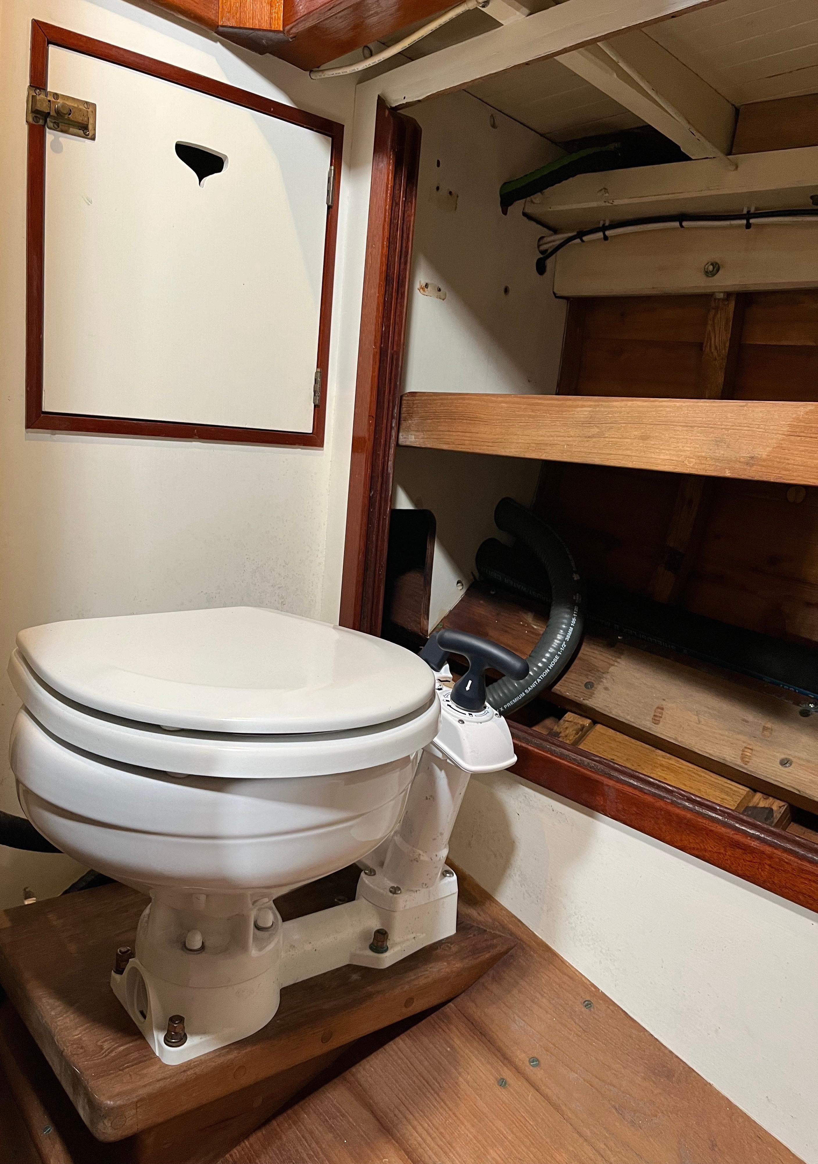 1999 Custom Lyle Hess Cutter boat interior with marine toilet and wooden storage shelves.