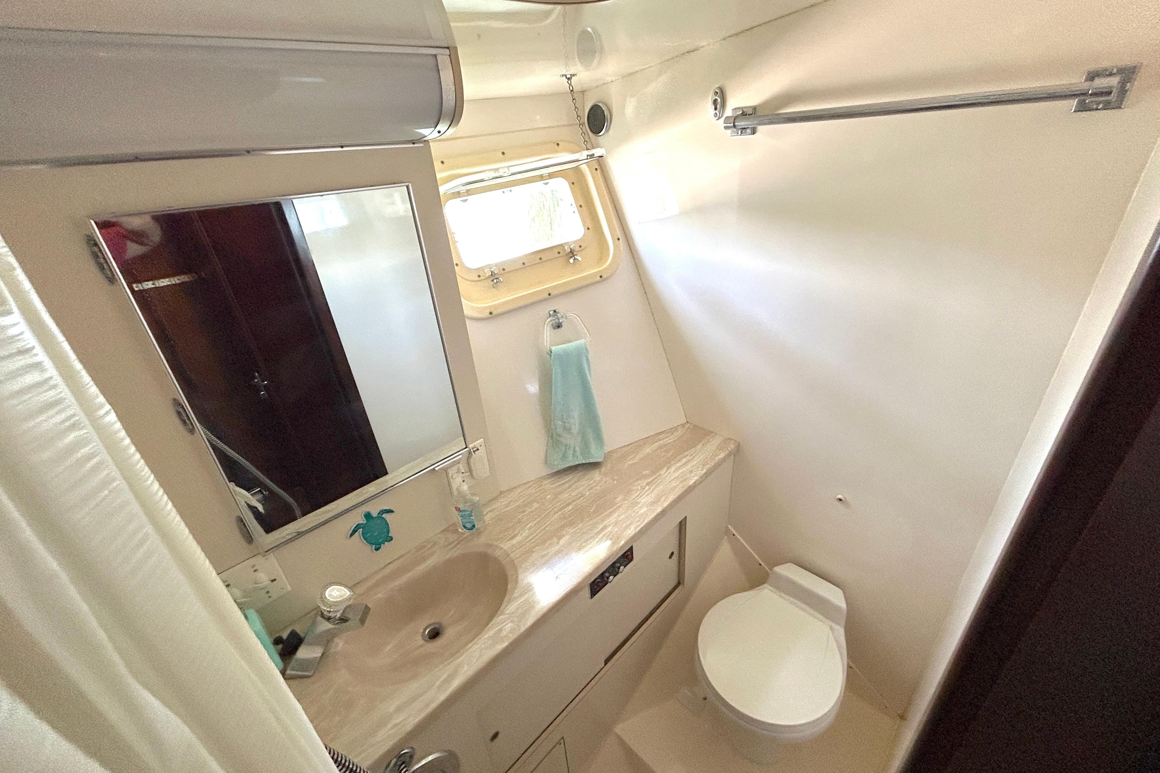Bathroom interior of 1989 Hatteras 45 Convertible yacht, featuring sink, mirror, and toilet.