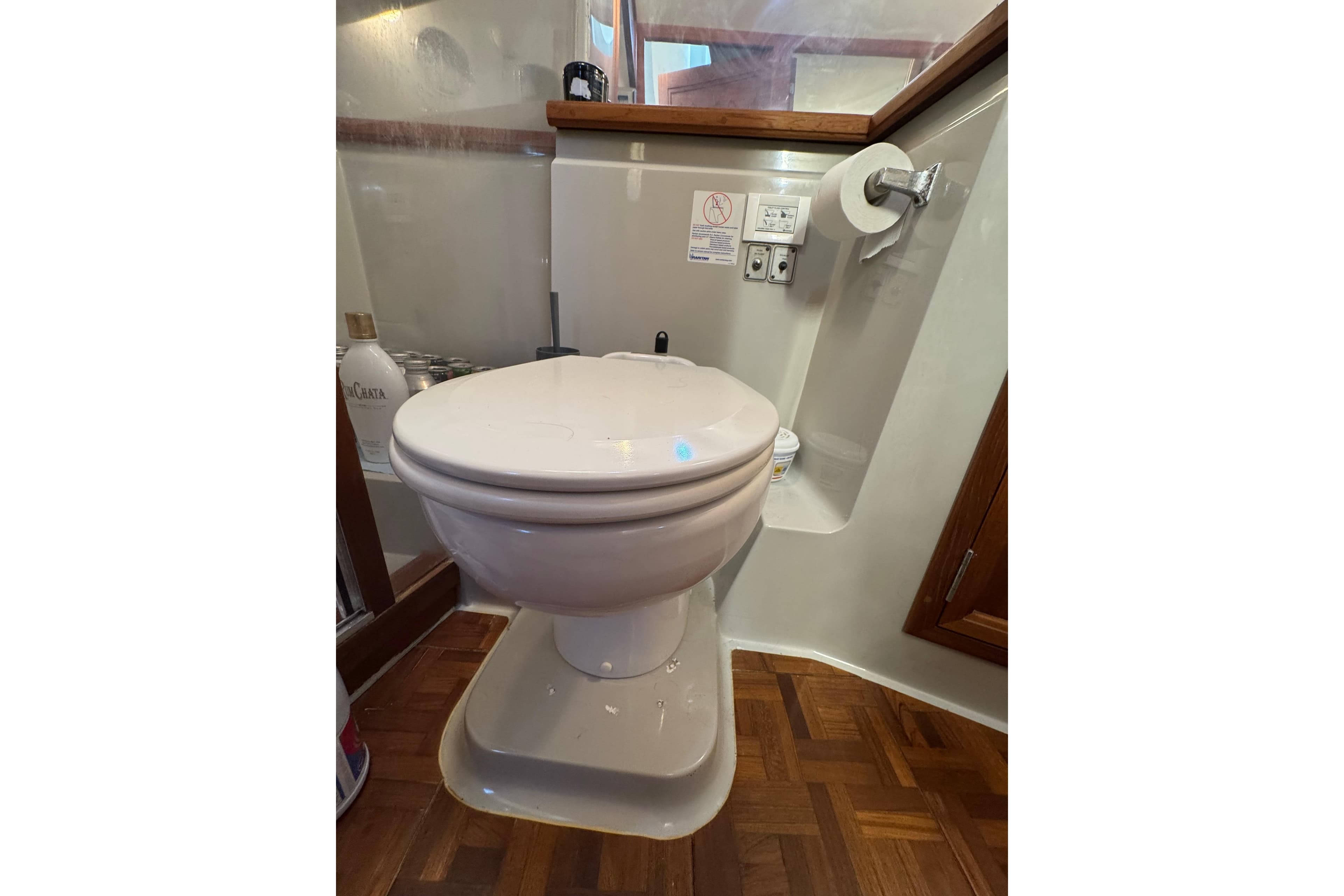 Toilet in 1986 Carver 42 Aft Cabin Motor Yacht bathroom with wooden flooring.