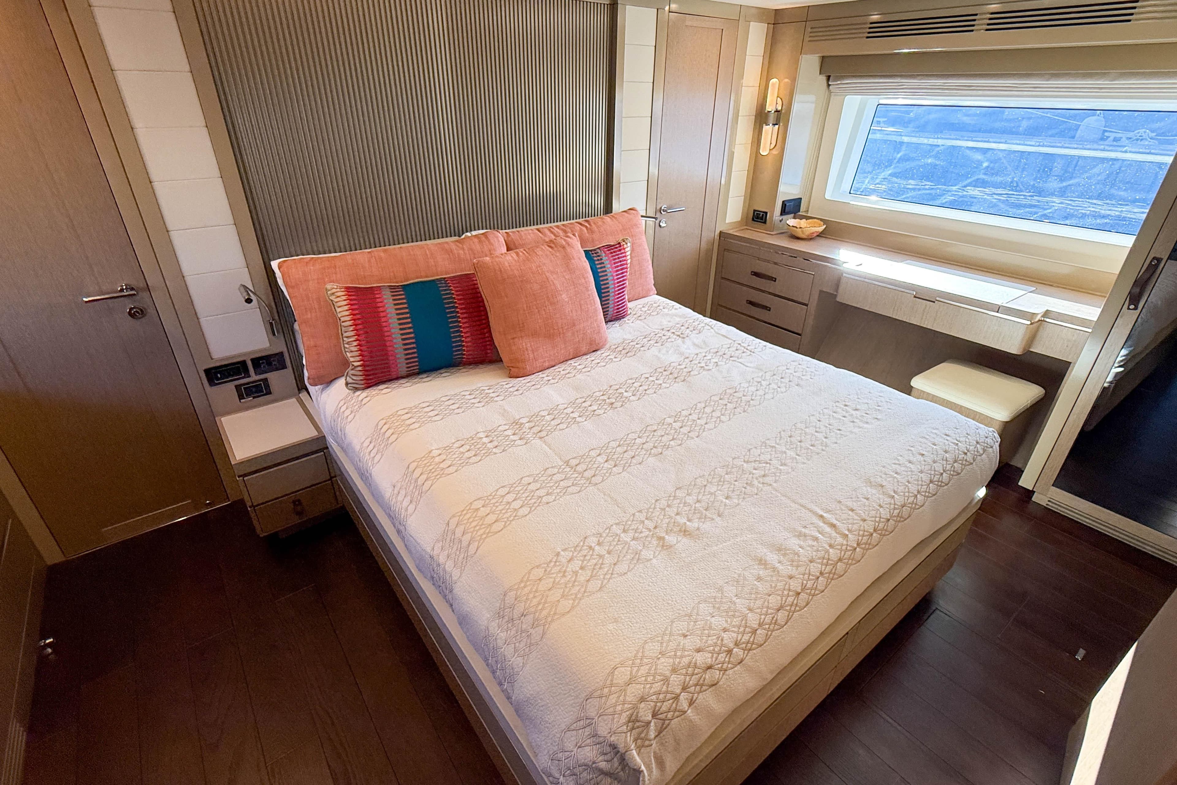 Luxurious bedroom interior of 2023 Sirena 68 yacht with elegant decor and large window.