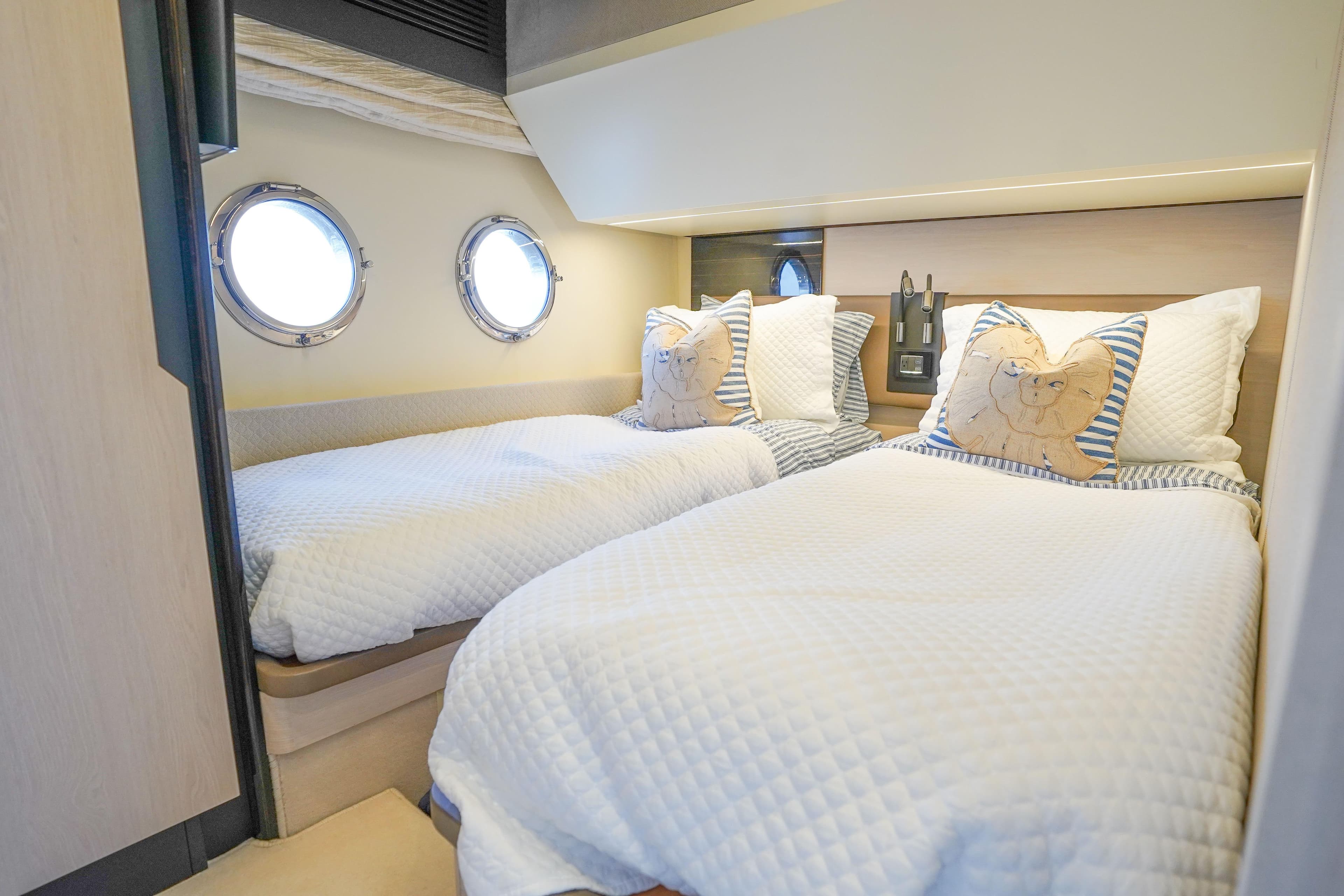 Cozy twin bedroom in 2017 Azimut 66 Flybridge yacht with porthole windows.
