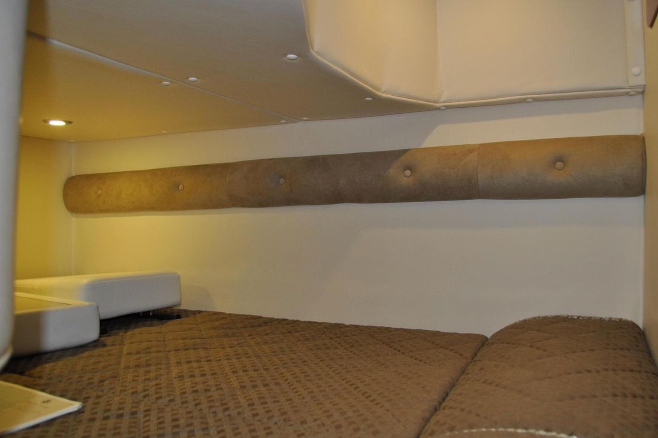 2012 Rinker 310 Express Cruiser cabin interior with cozy bedding and ambient lighting.