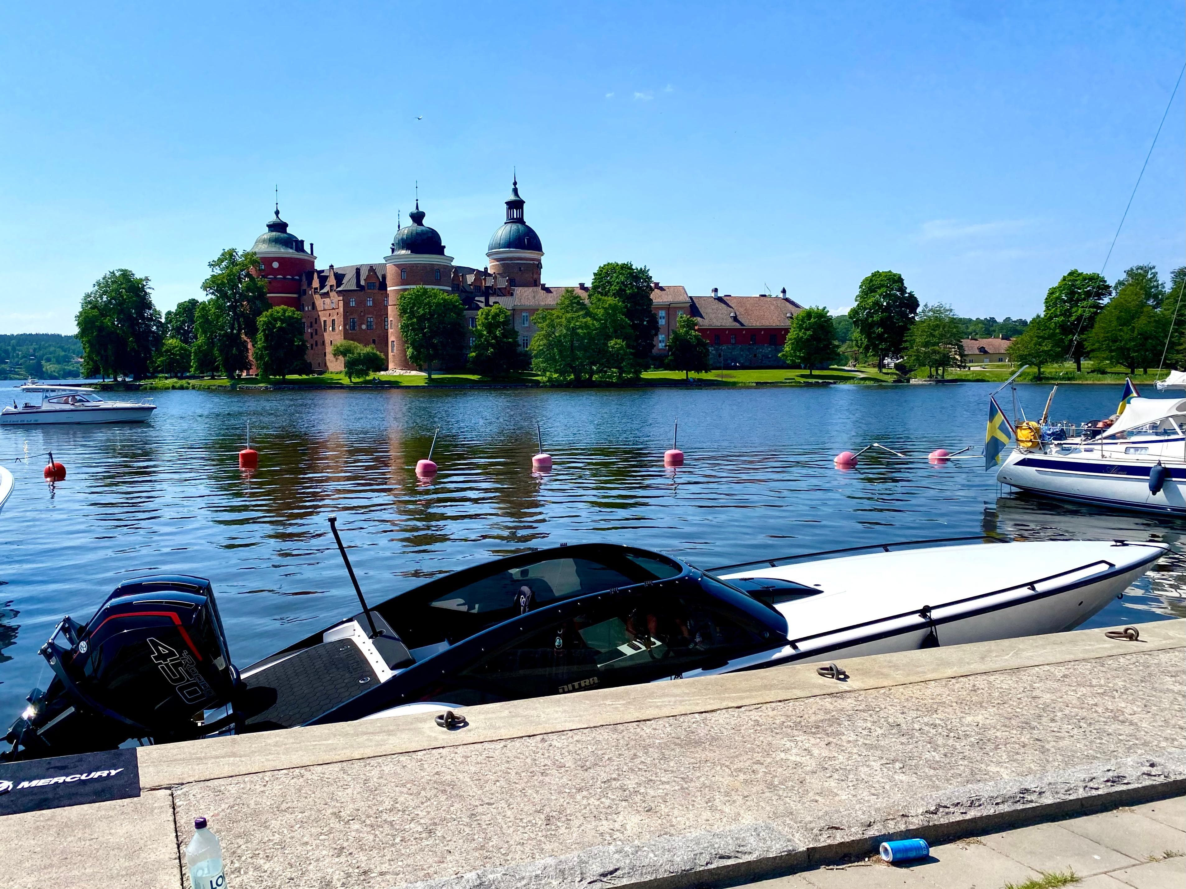 2022 Nitra Boats 30 SkyTop docked by a scenic castle and lake.