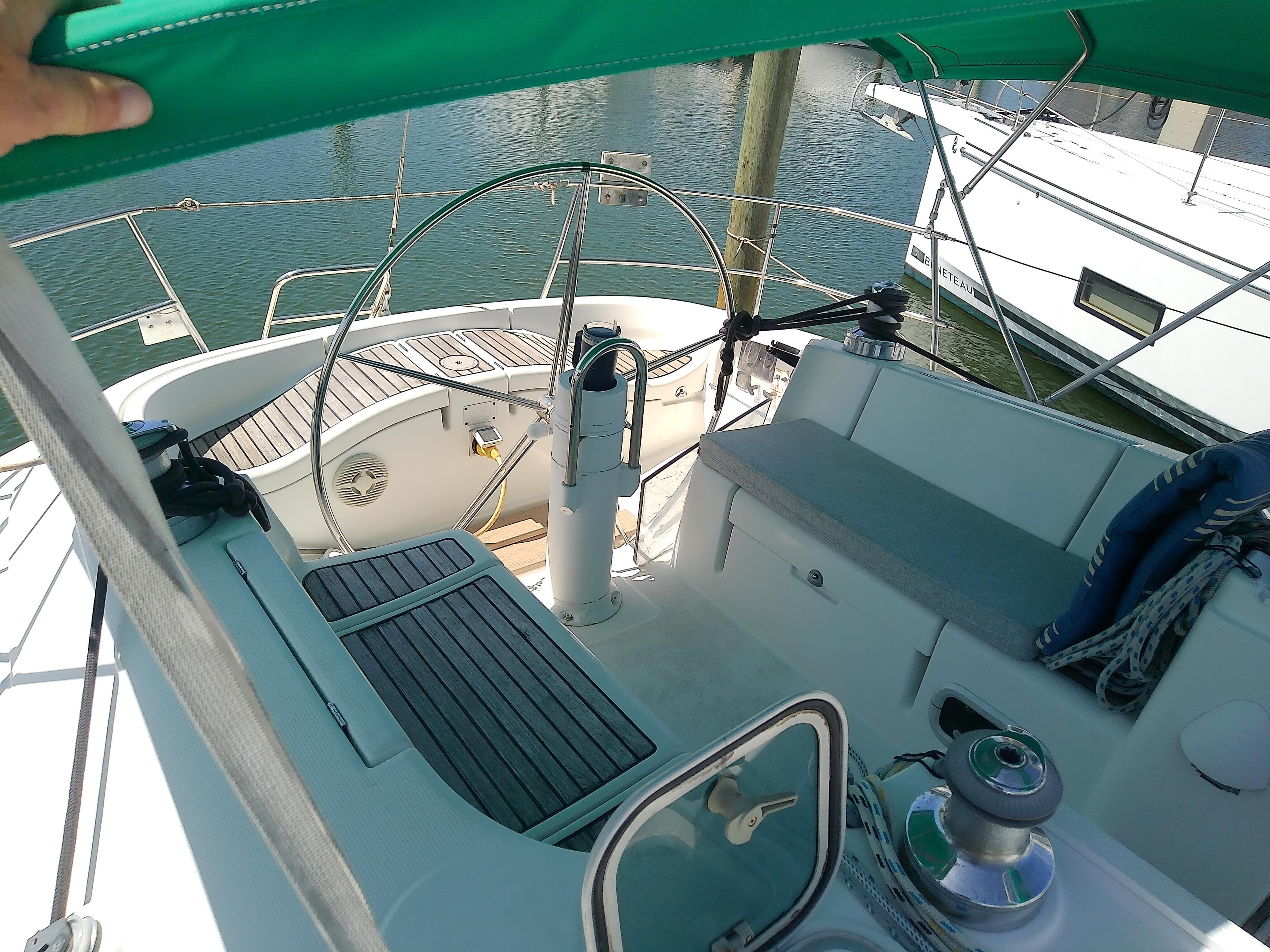 Cockpit of 1995 Beneteau First 42s7 sailboat with green canopy and wooden deck.
