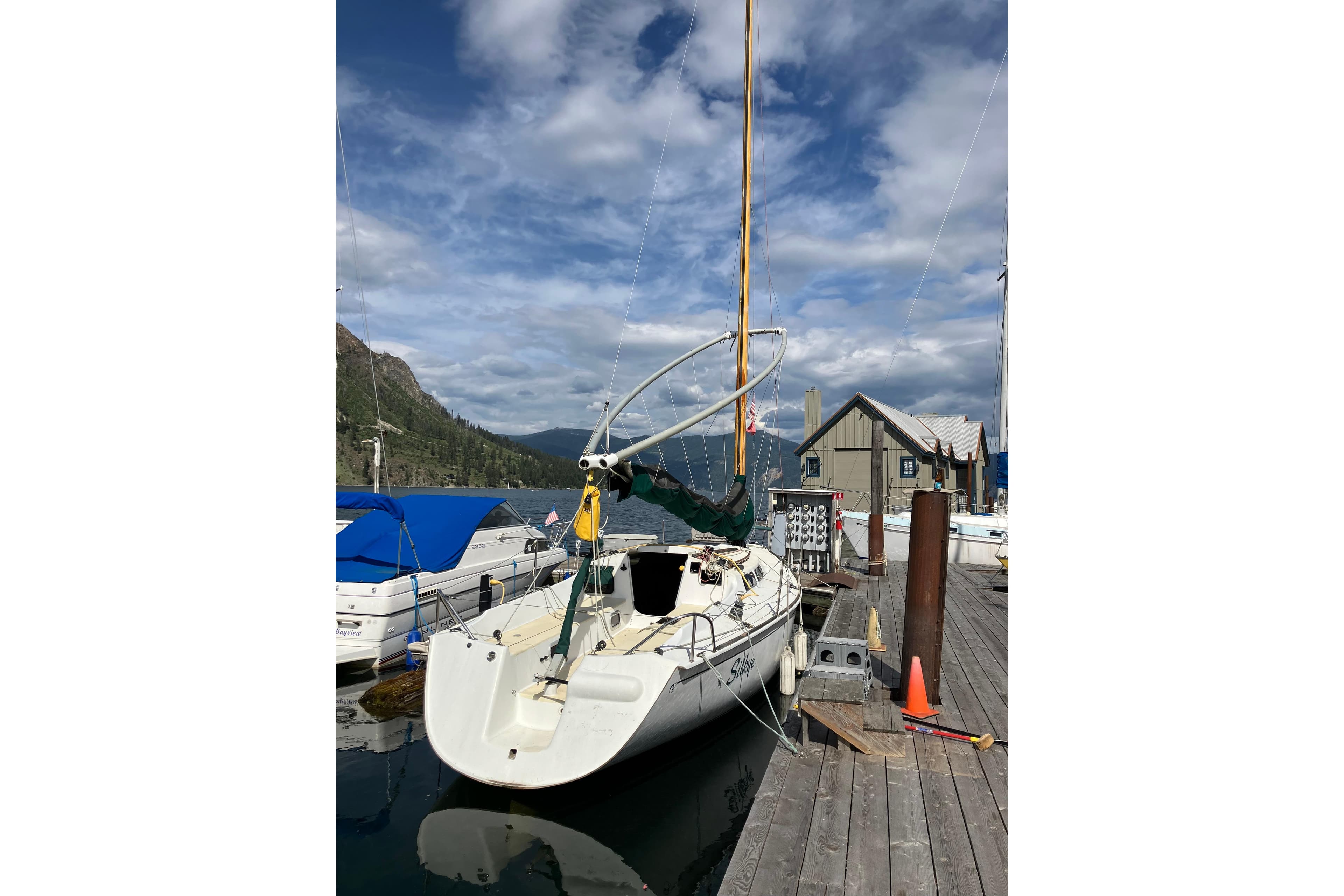 1996 Wylie 30 sailboat docked at a marina with scenic mountain backdrop.