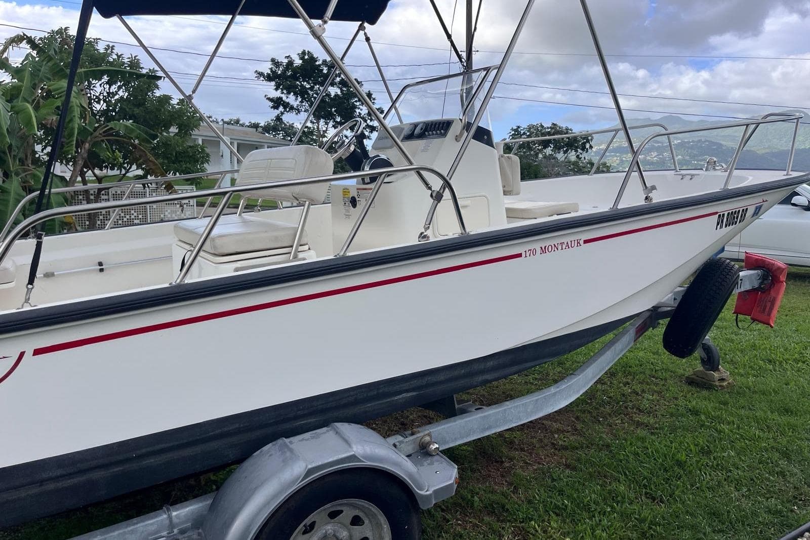 2020 Boston Whaler 170 Montauk boat on trailer, parked on grass.