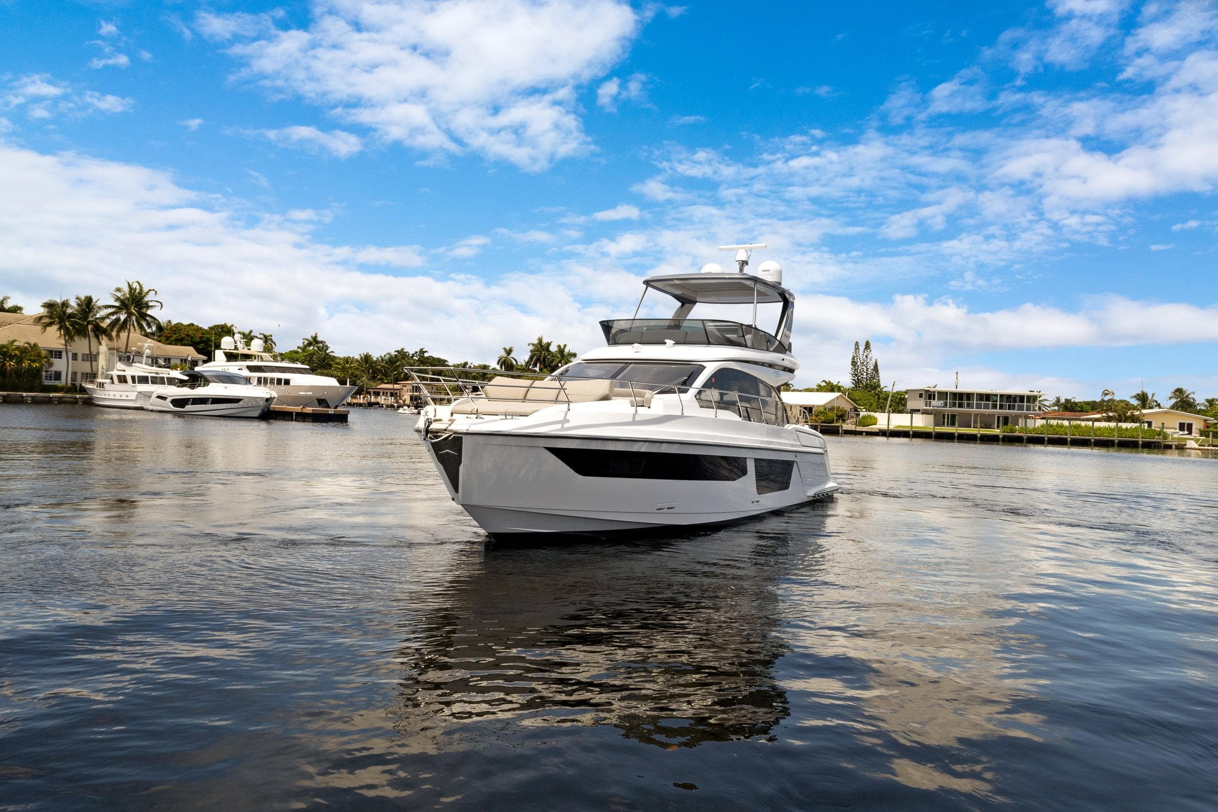 2024 Azimut Fly 53 yacht cruising on a sunny day, surrounded by waterfront homes.