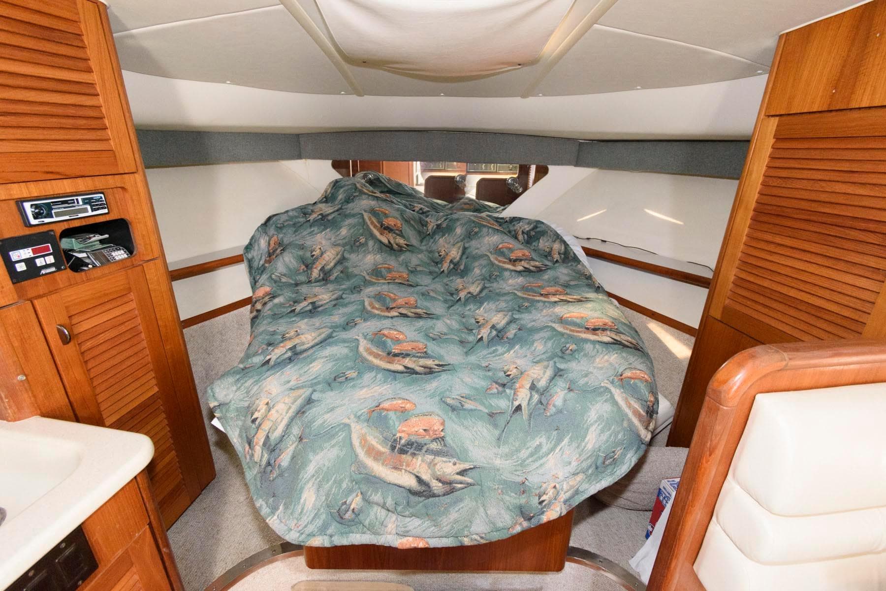 Interior cabin of 2000 Pursuit 3400 Express with fish-patterned bedspread.