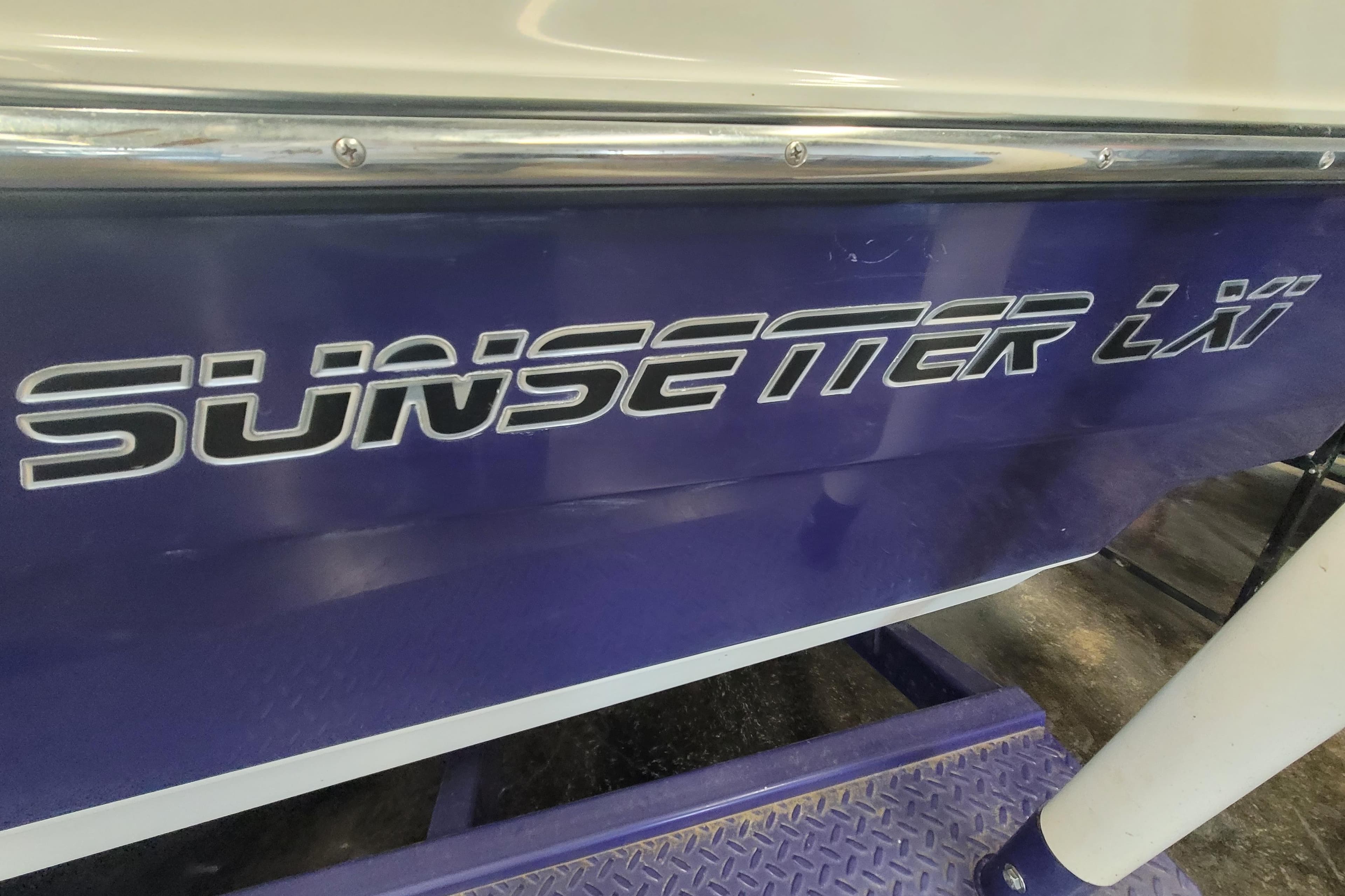2003 Malibu Sunsetter LXi boat with bold logo on blue hull.