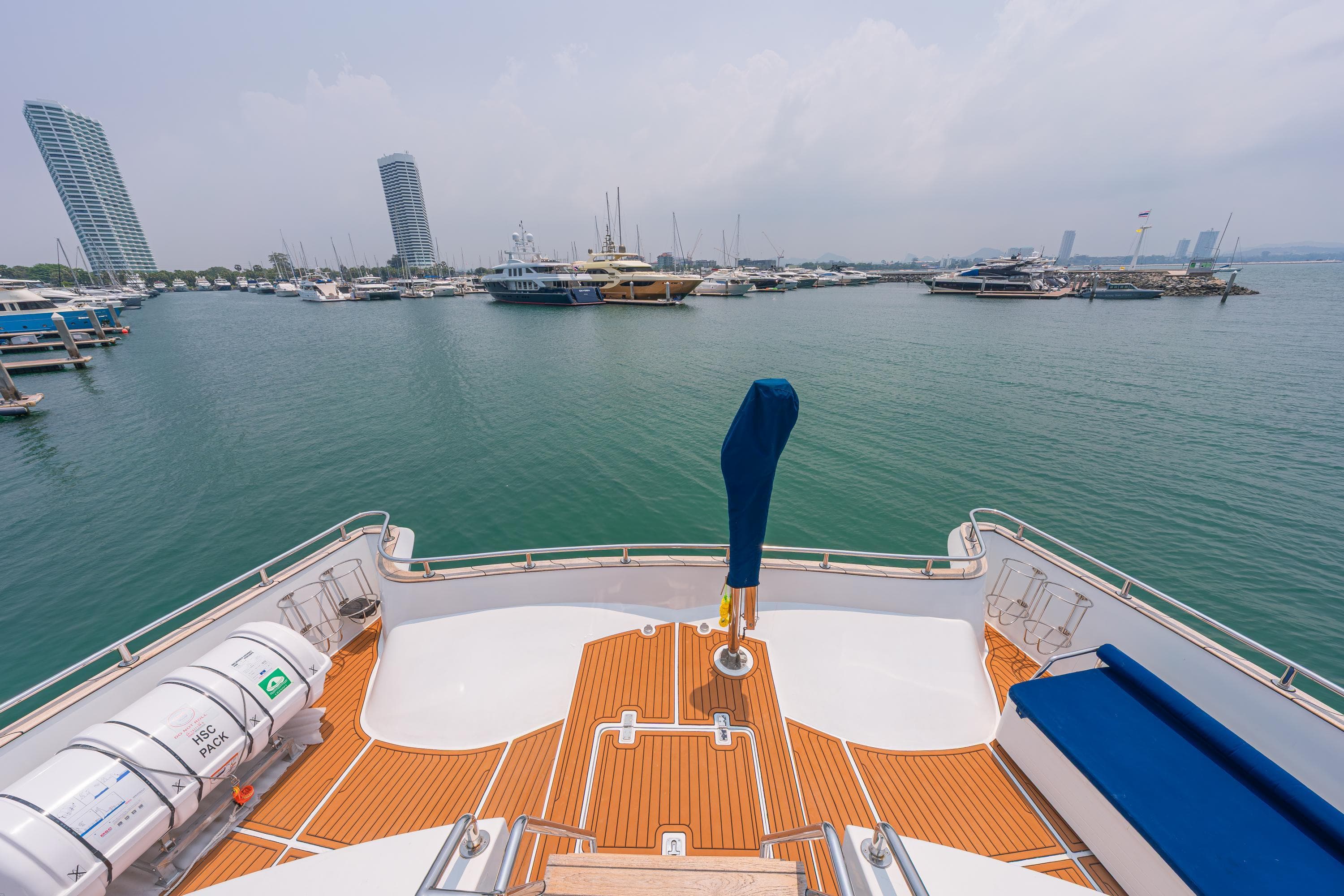 Bow view of 2023 Custom Courage 82 yacht in a marina, with city skyline.