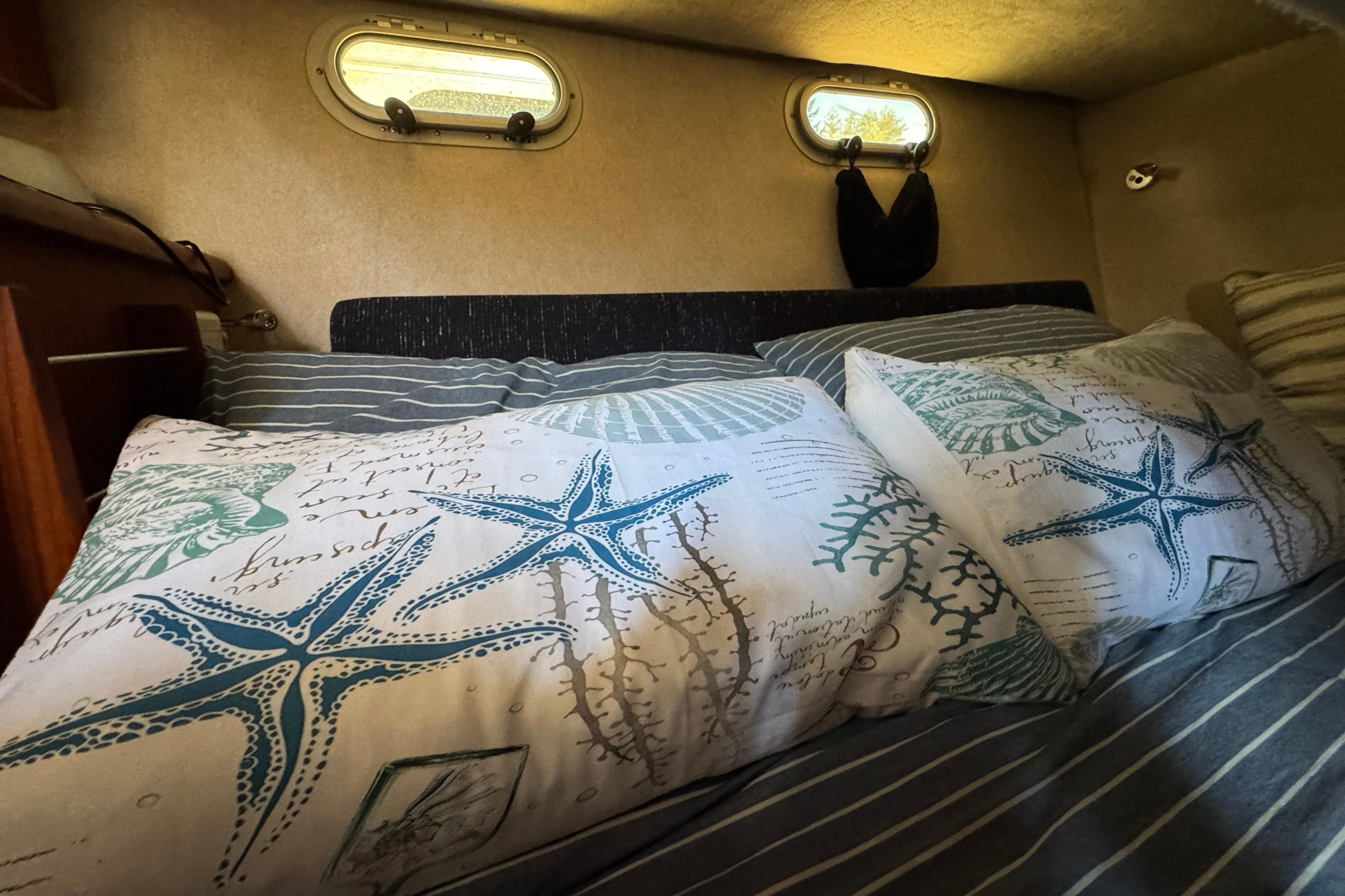 Cozy cabin interior of 1995 Bayliner 3288 Motoryacht with nautical-themed bedding.