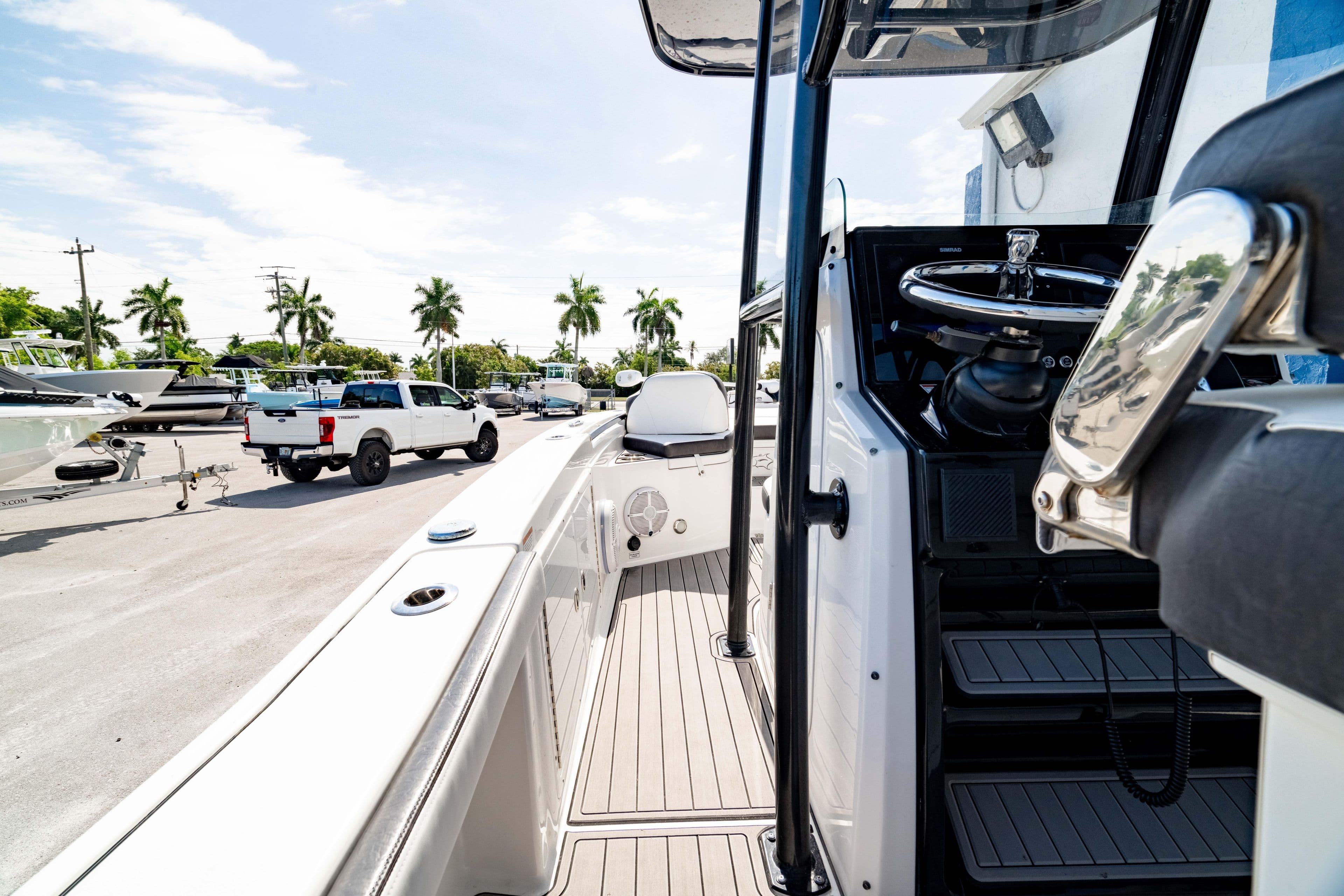 2023 Crevalle 26 HCO boat interior with steering wheel, parked near palm trees.