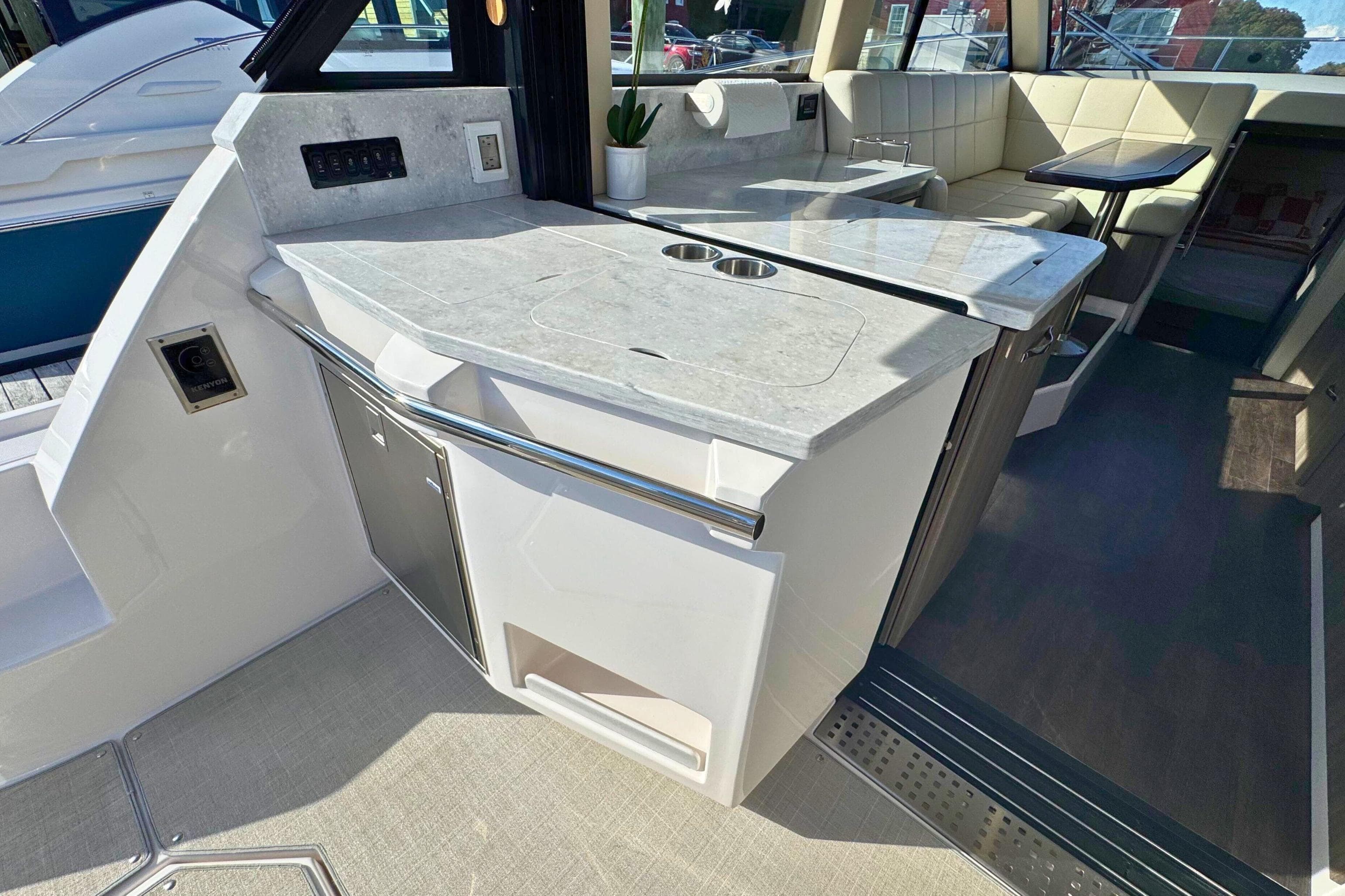 Interior of 2021 Regal 38 Grande Coupe yacht with modern kitchenette and seating area.