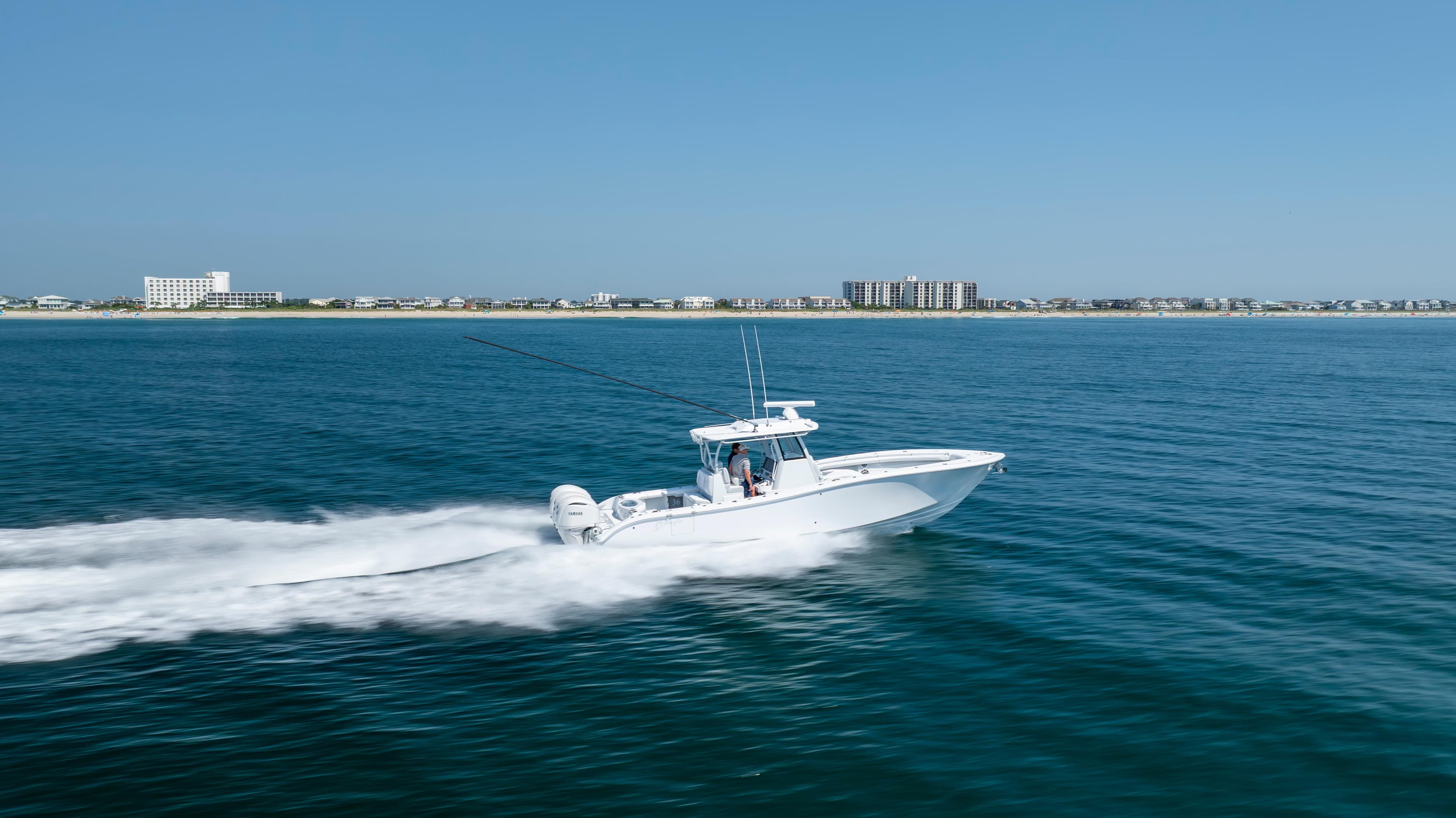 2026 Yellowfin 36 Offshore boat cruising on open water near coastal buildings.