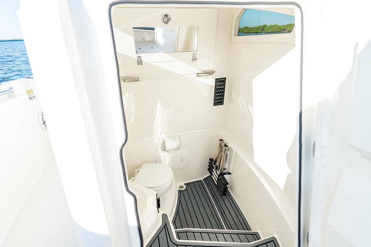 Manufacturer Provided Image: 2026 Cobia 245 Center Console boat interior with toilet and storage space.