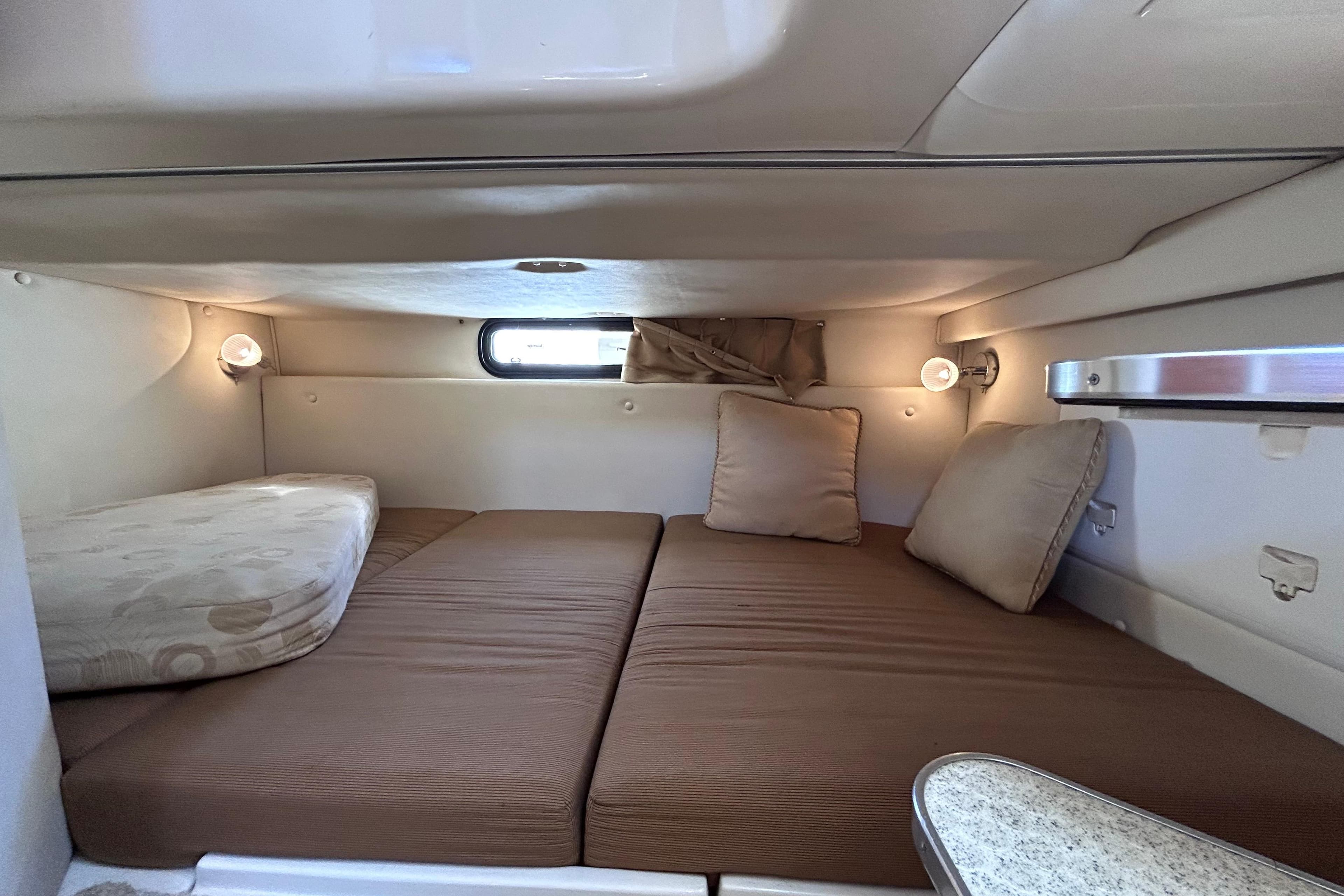 2006 Wellcraft 290 Coastal cabin interior with cozy bedding and ambient lighting.
