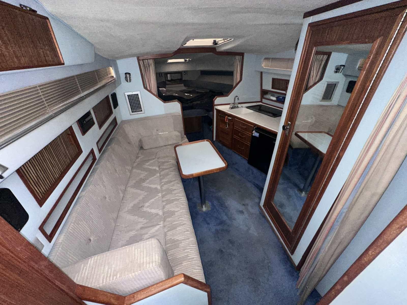Interior of a 1987 Sea Ray 270 Sundancer boat, featuring a cozy cabin with seating and kitchenette.