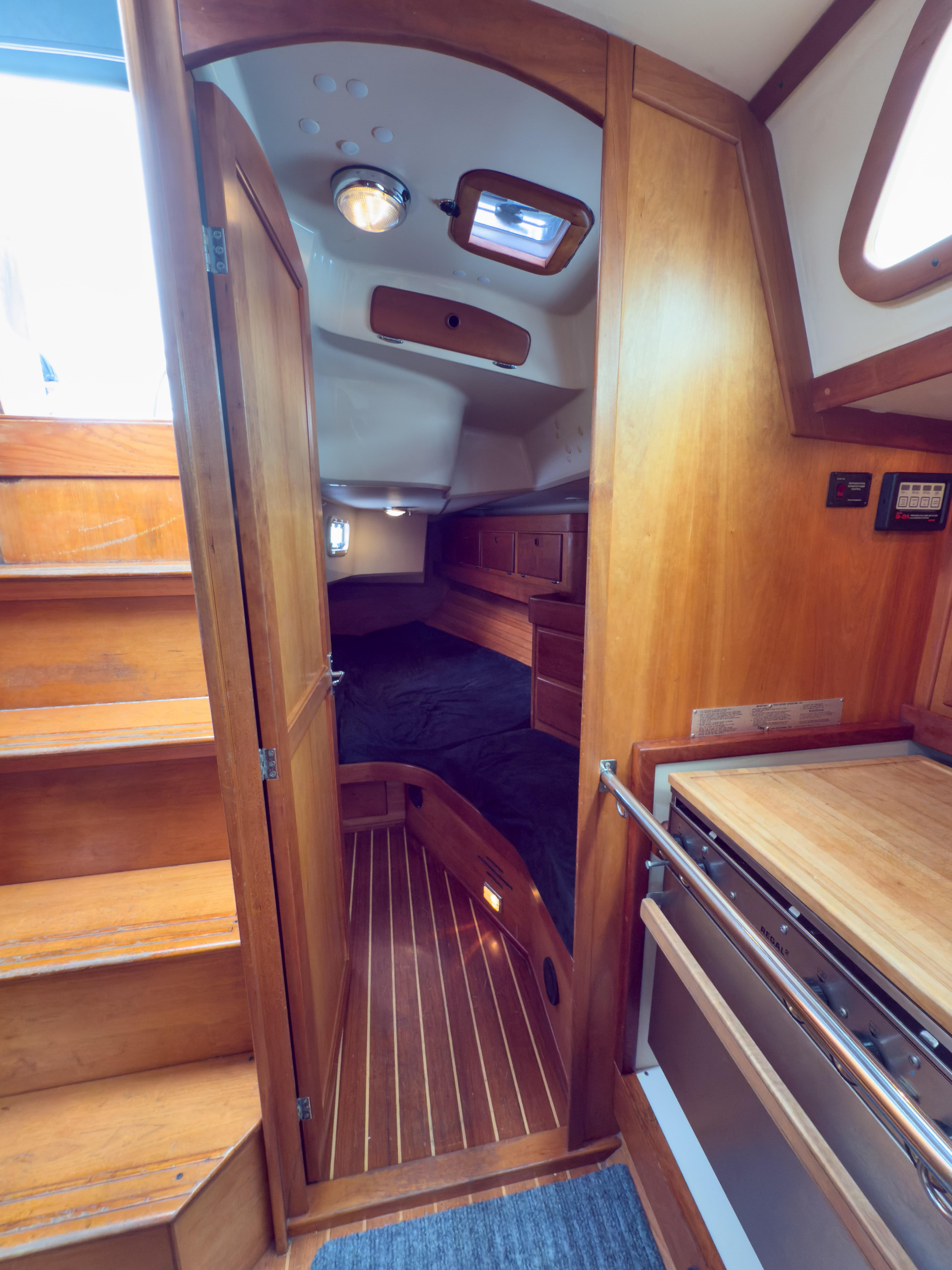 Interior of a 1997 Sabre 402 sailboat, featuring wooden cabinetry and cozy sleeping quarters.