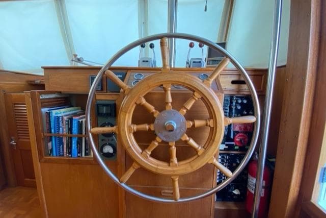 Wooden helm of a 1977 Grand Banks 42 yacht, with navigation equipment and books.