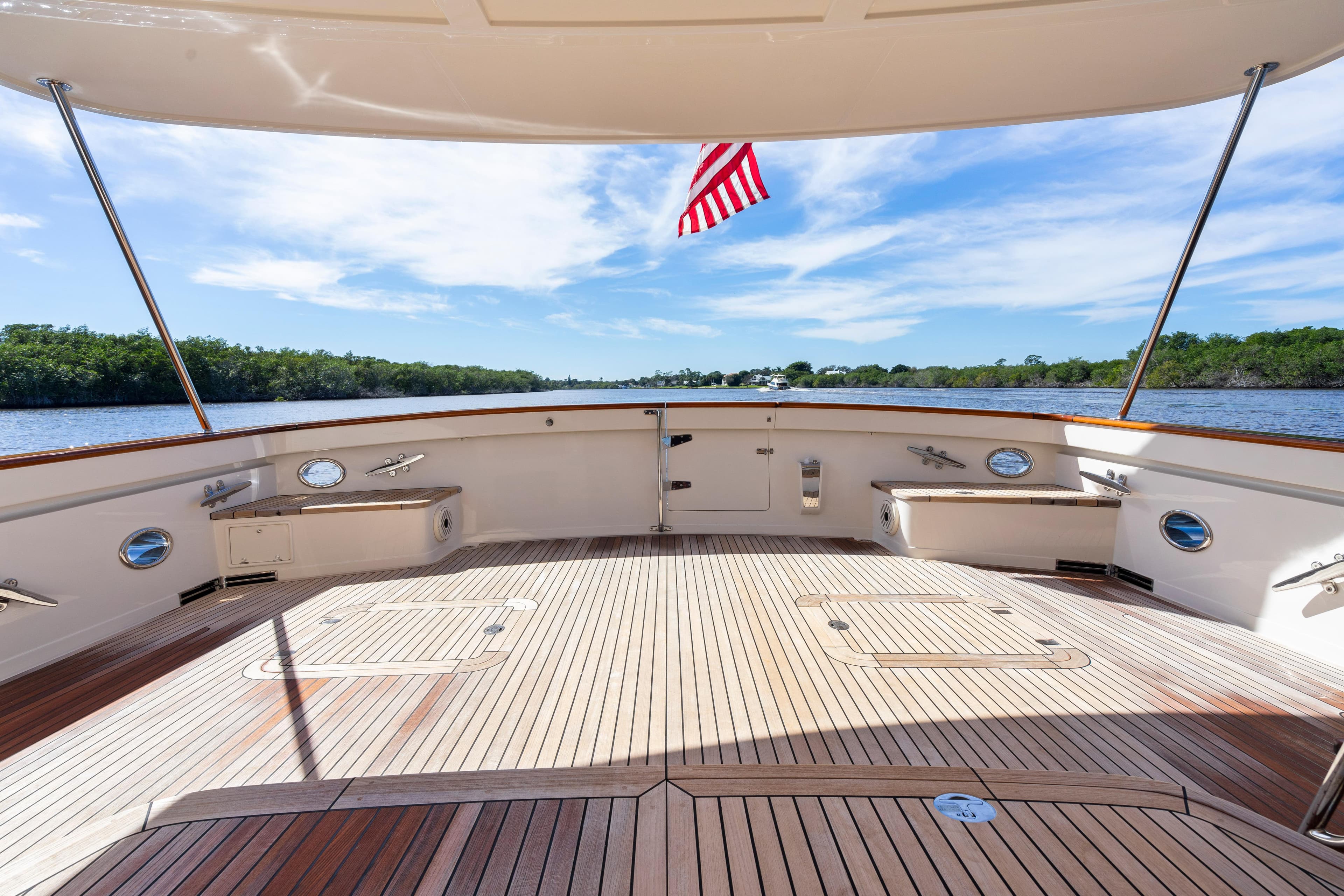 Spacious deck of 2023 Fleming 65 yacht with American flag, overlooking serene waters.