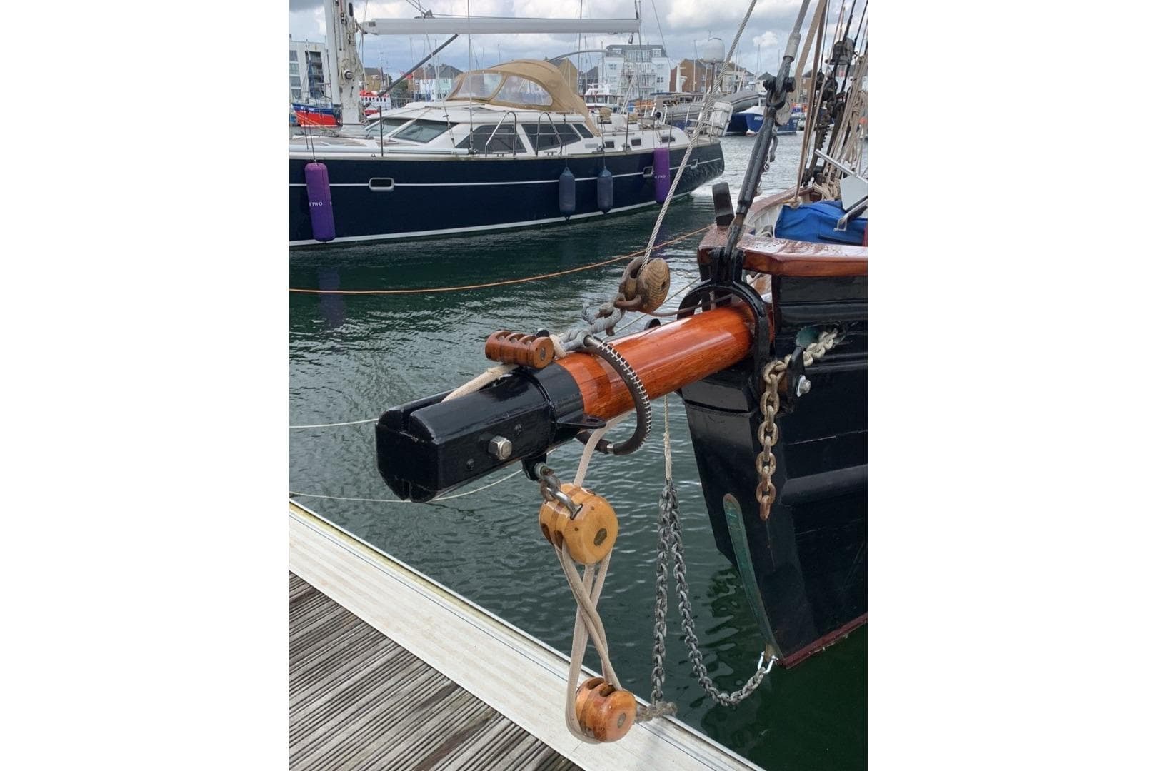 Classic 1899 Bristol Pilot Cutter docked, showcasing detailed rigging and wooden bowsprit.