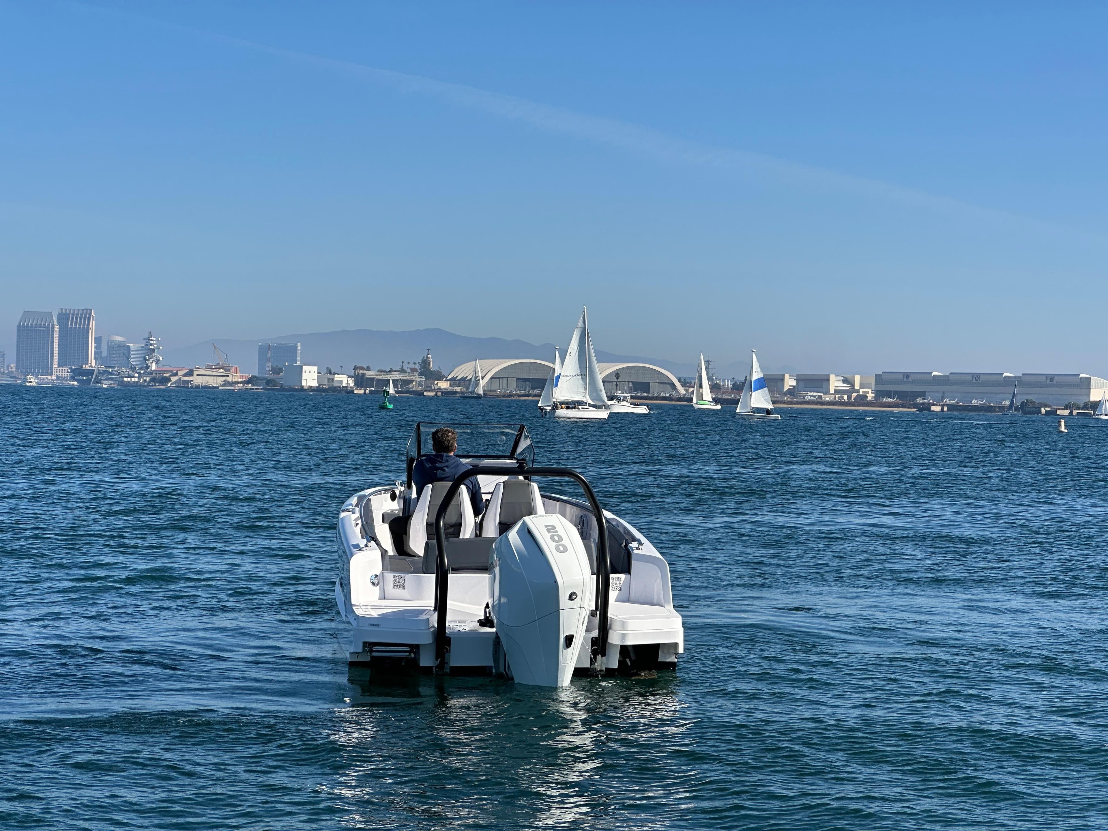 2021 Axopar 22 Spyder on open water with cityscape and sailboats in background.