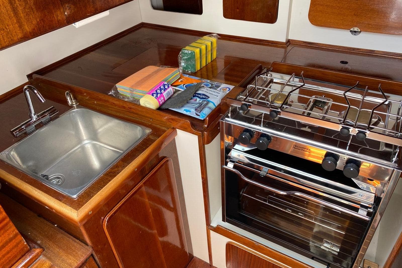 1972 CRAGLIETTO One Tonner yacht kitchen with sink, stove, and cleaning supplies.