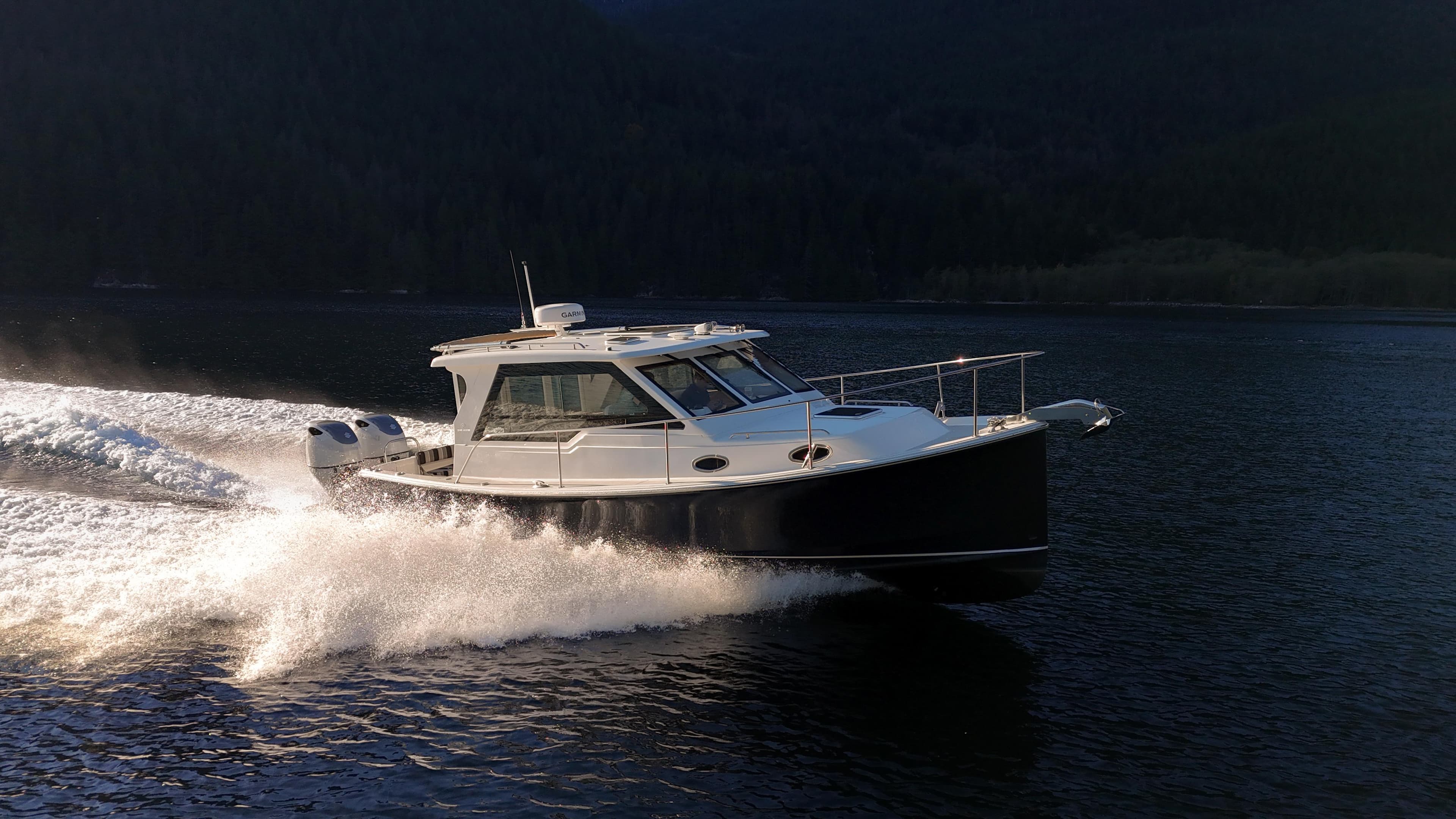 2025 True North 34 Outboard Express cruising on a serene lake at high speed.