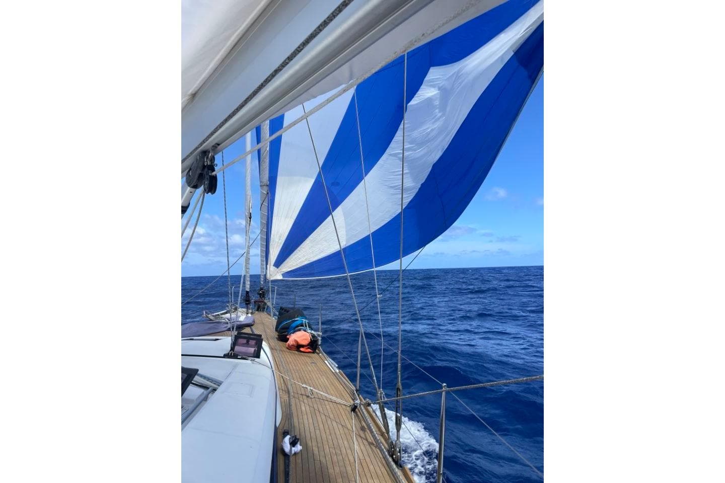 Sailing on a 2015 Beneteau Sense 55 with blue and white sails over open ocean.