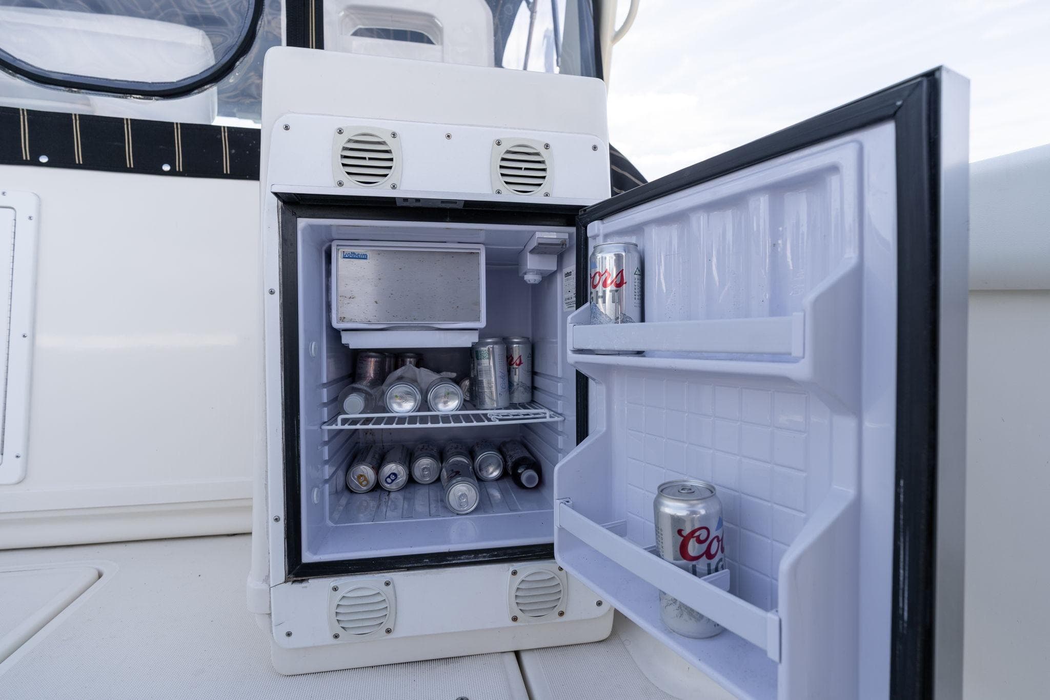 Open mini fridge on 1998 Tiara Yachts 3500 Express, stocked with beverages.