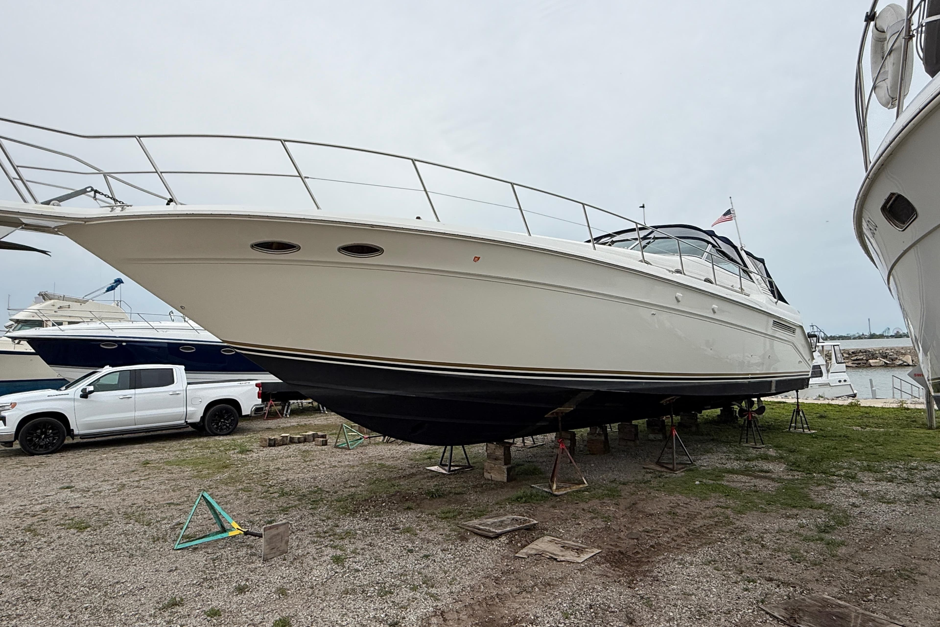 1998 Sea Ray 500 Sundancer yacht on dry dock, side view with overcast sky.