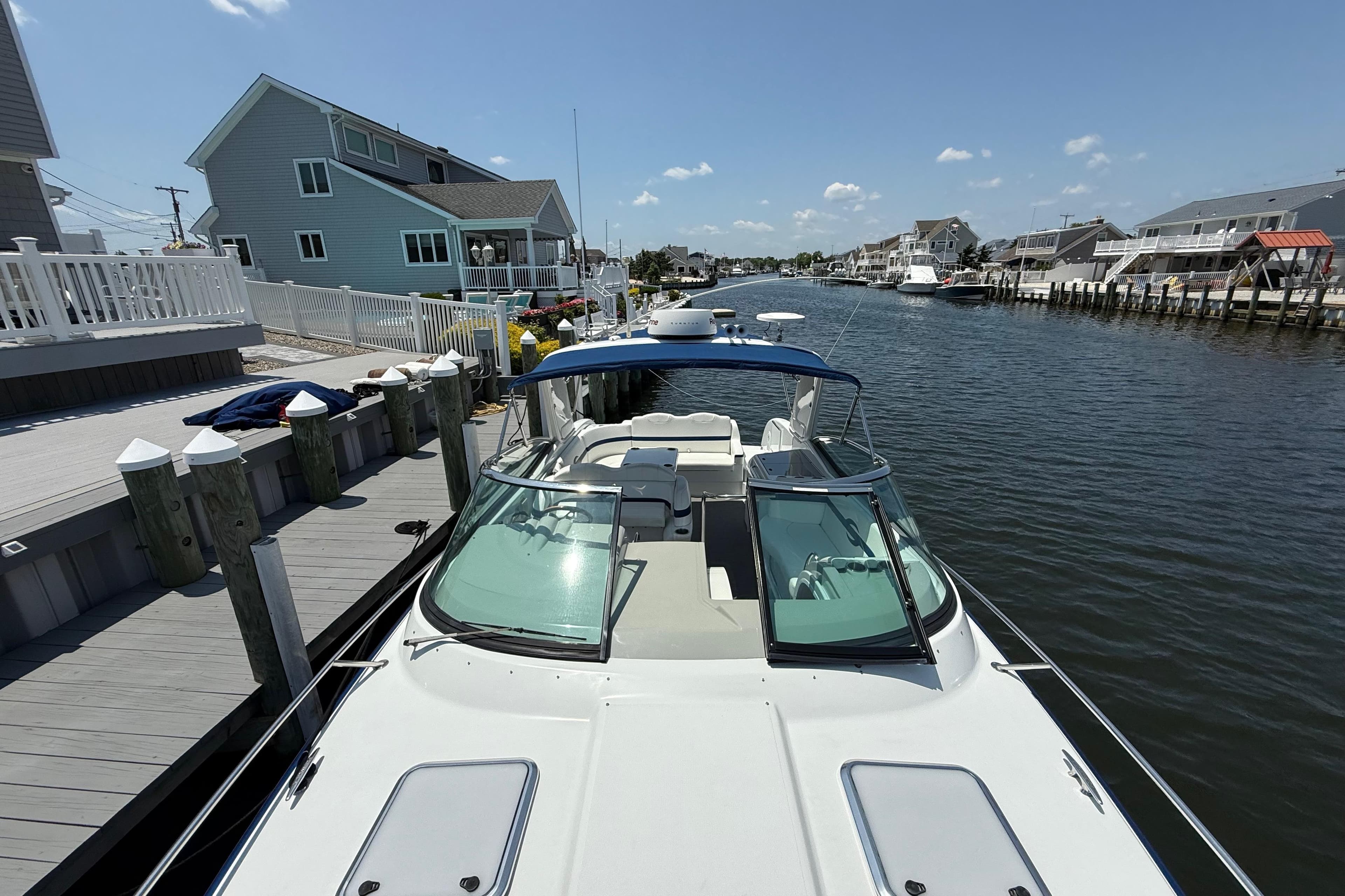 2012 Formula 350 Sun Sport docked by waterfront homes under a clear blue sky.