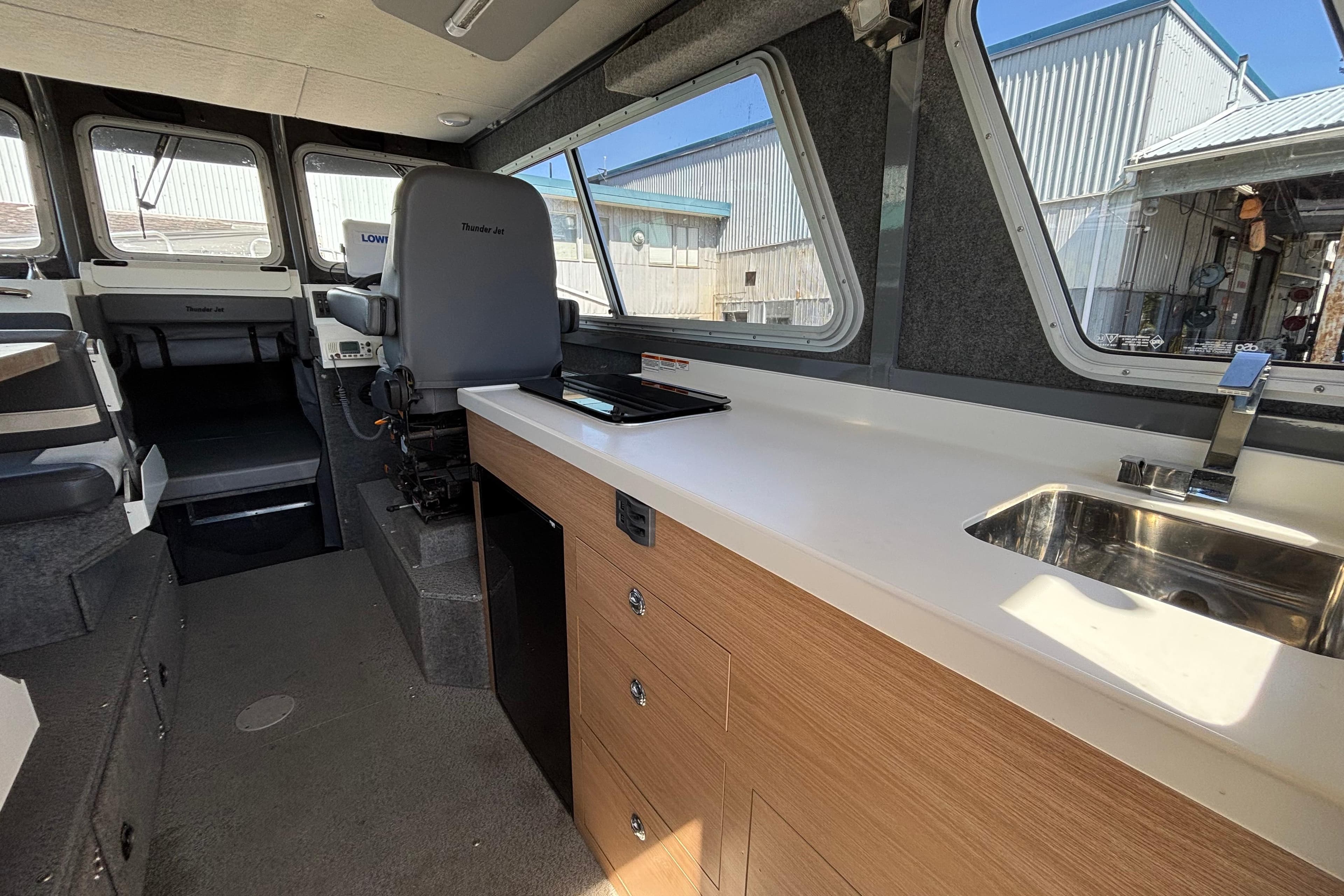 2021 Thunder Jet 28 Pilot interior with helm, kitchenette, and seating area.