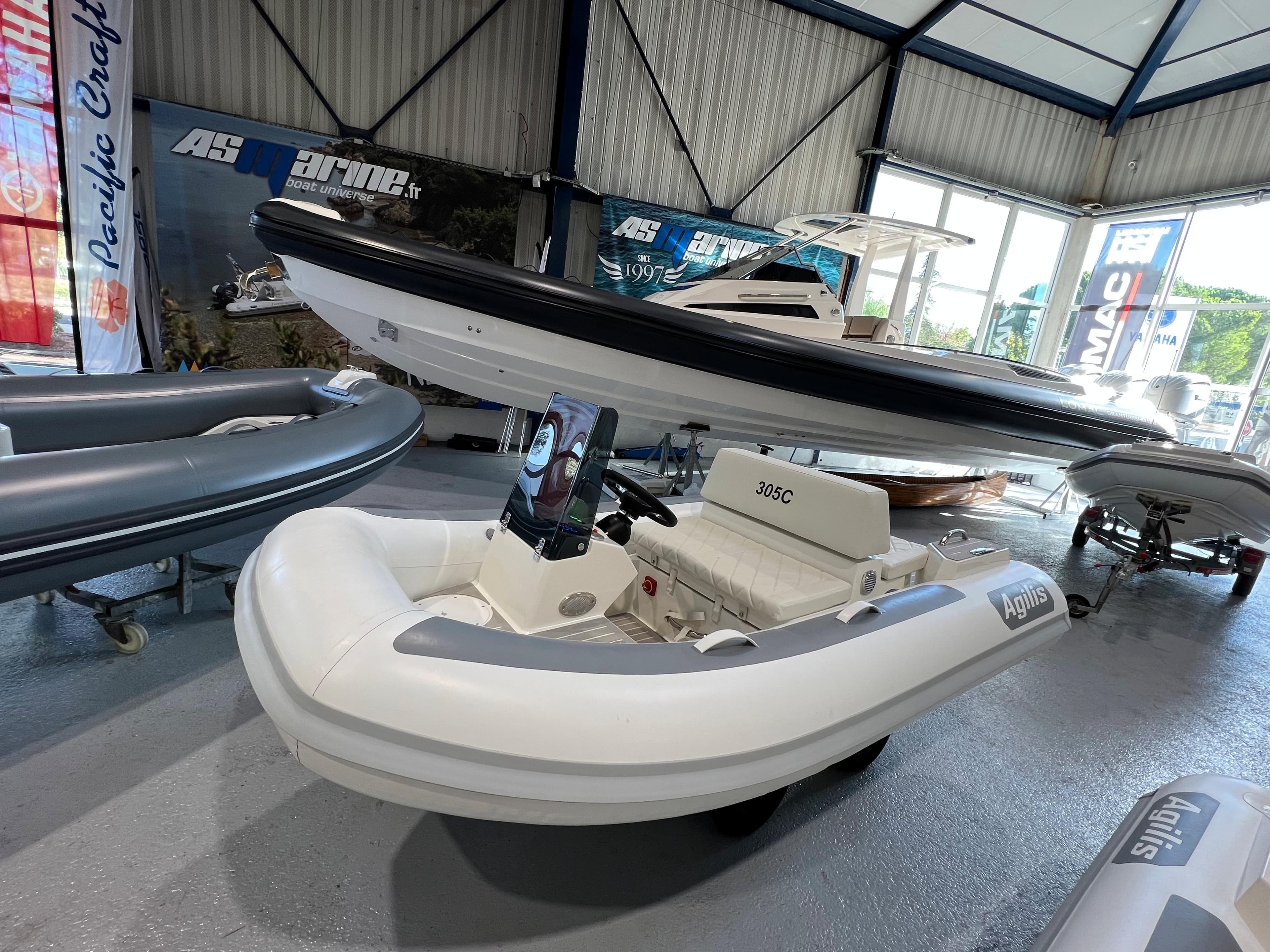 2025 Agilis 305 inflatable boat displayed in a showroom with other vessels.