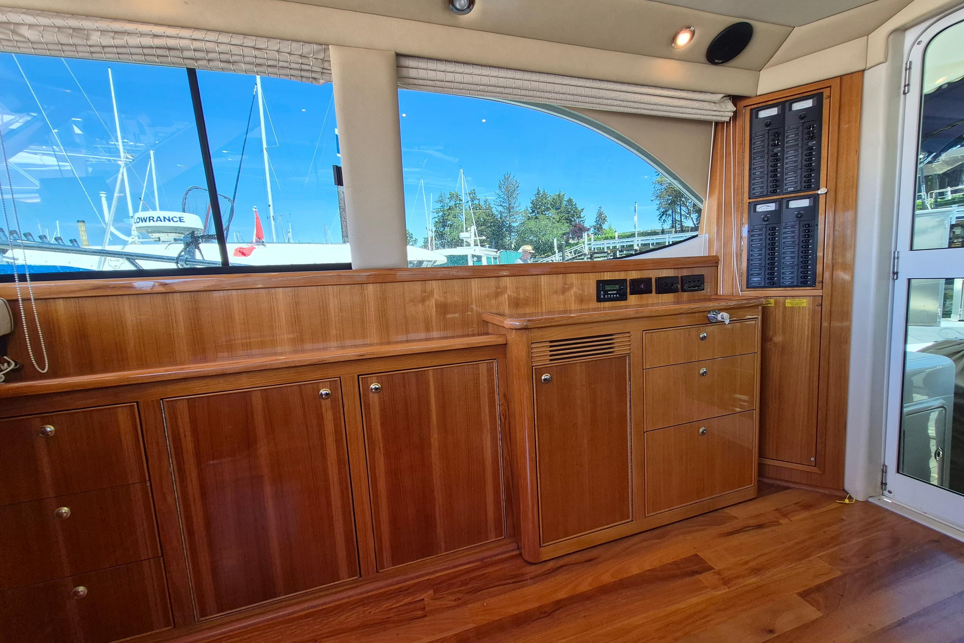 Interior of 2001 Riviera 40 Flybridge yacht with wooden cabinetry and large windows.