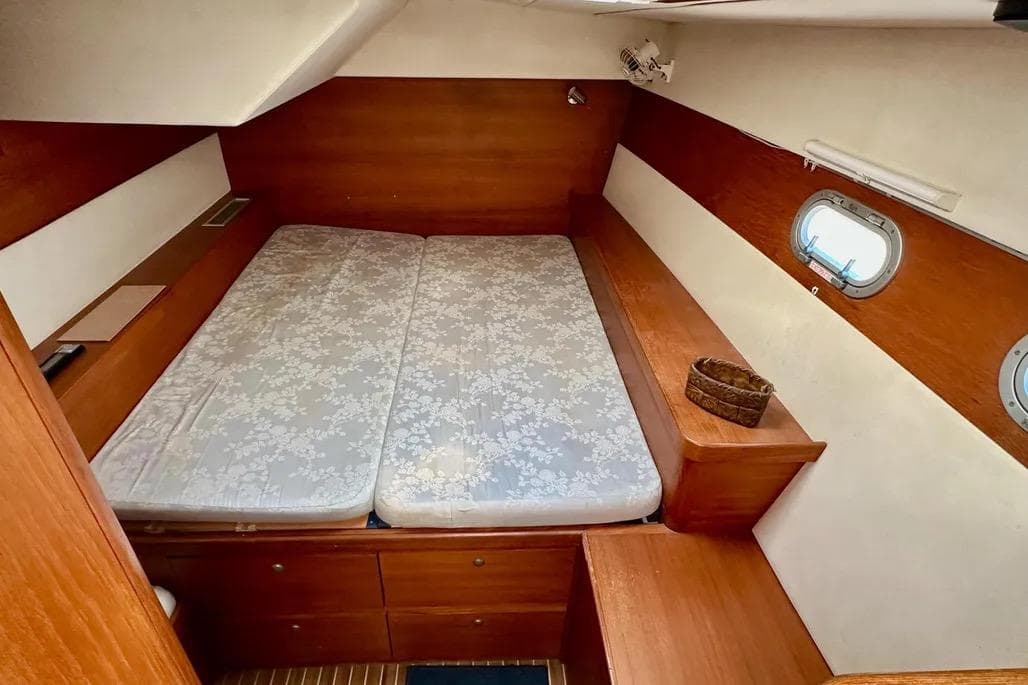 Cozy cabin interior of 2002 Lagoon 570 yacht with wooden finish and porthole window.