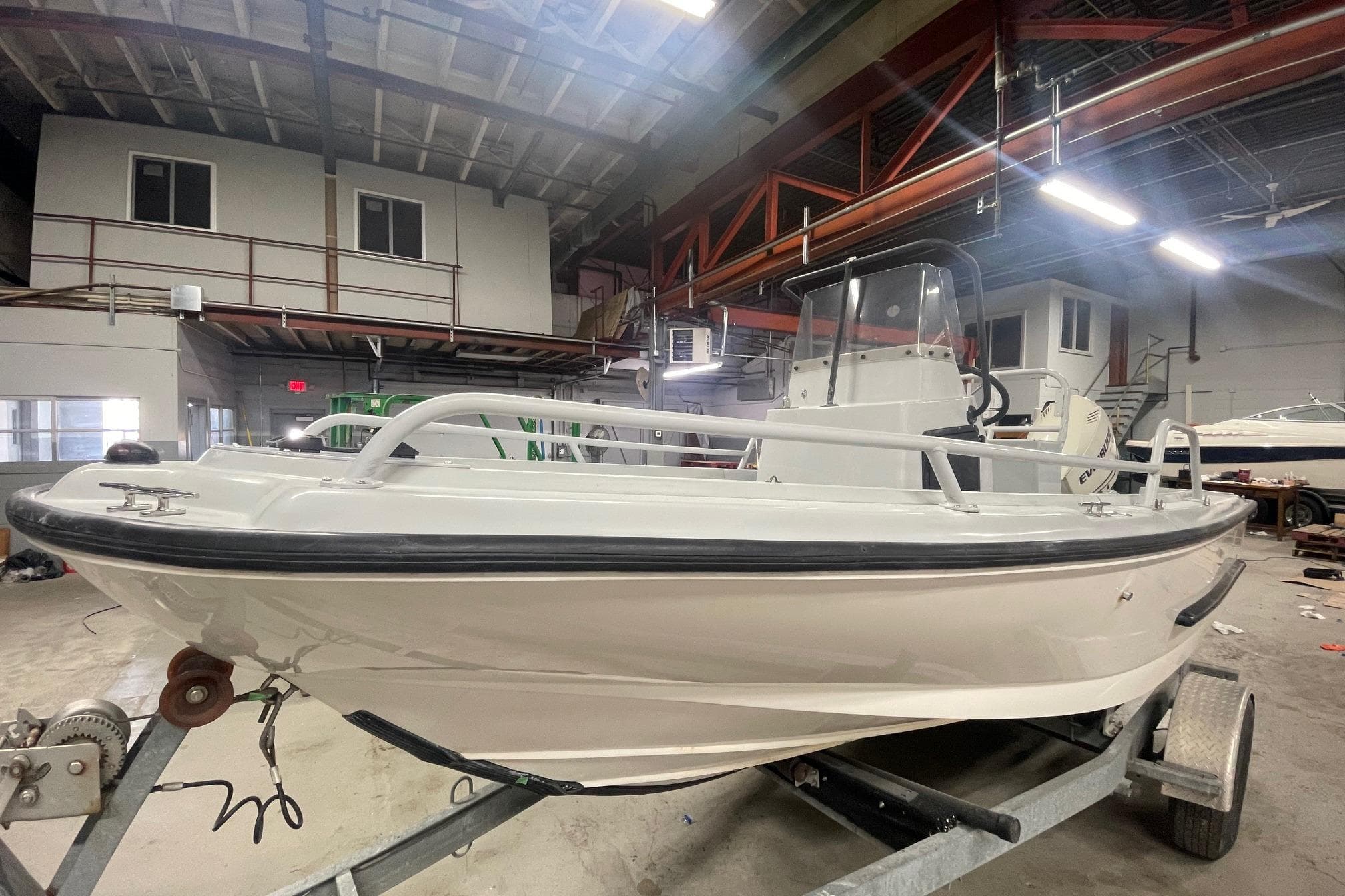 1995 Boston Whaler Justice boat on trailer in industrial warehouse setting.