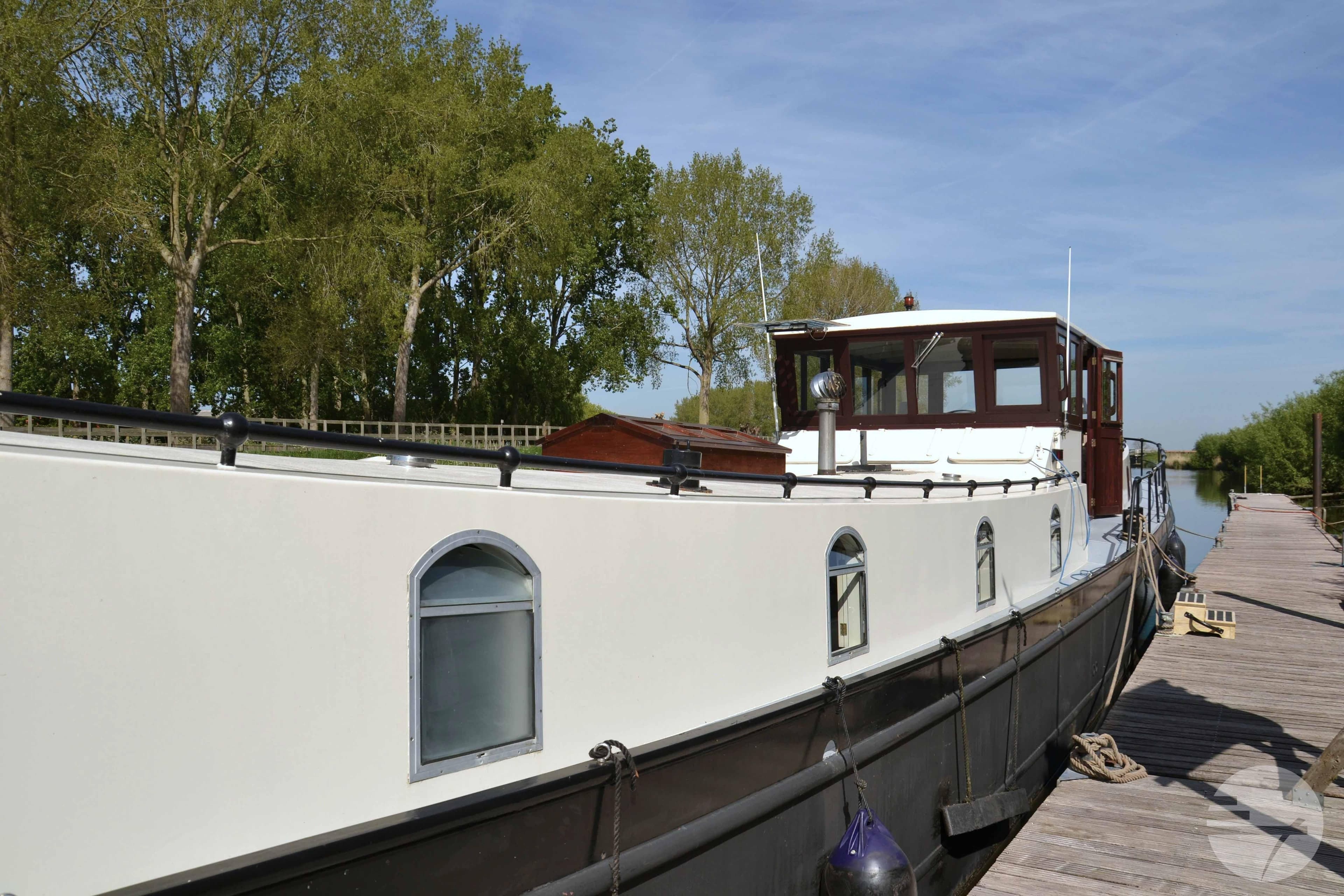 Custom 2010 Dutch Barge Replica moored by a wooden dock, surrounded by trees.