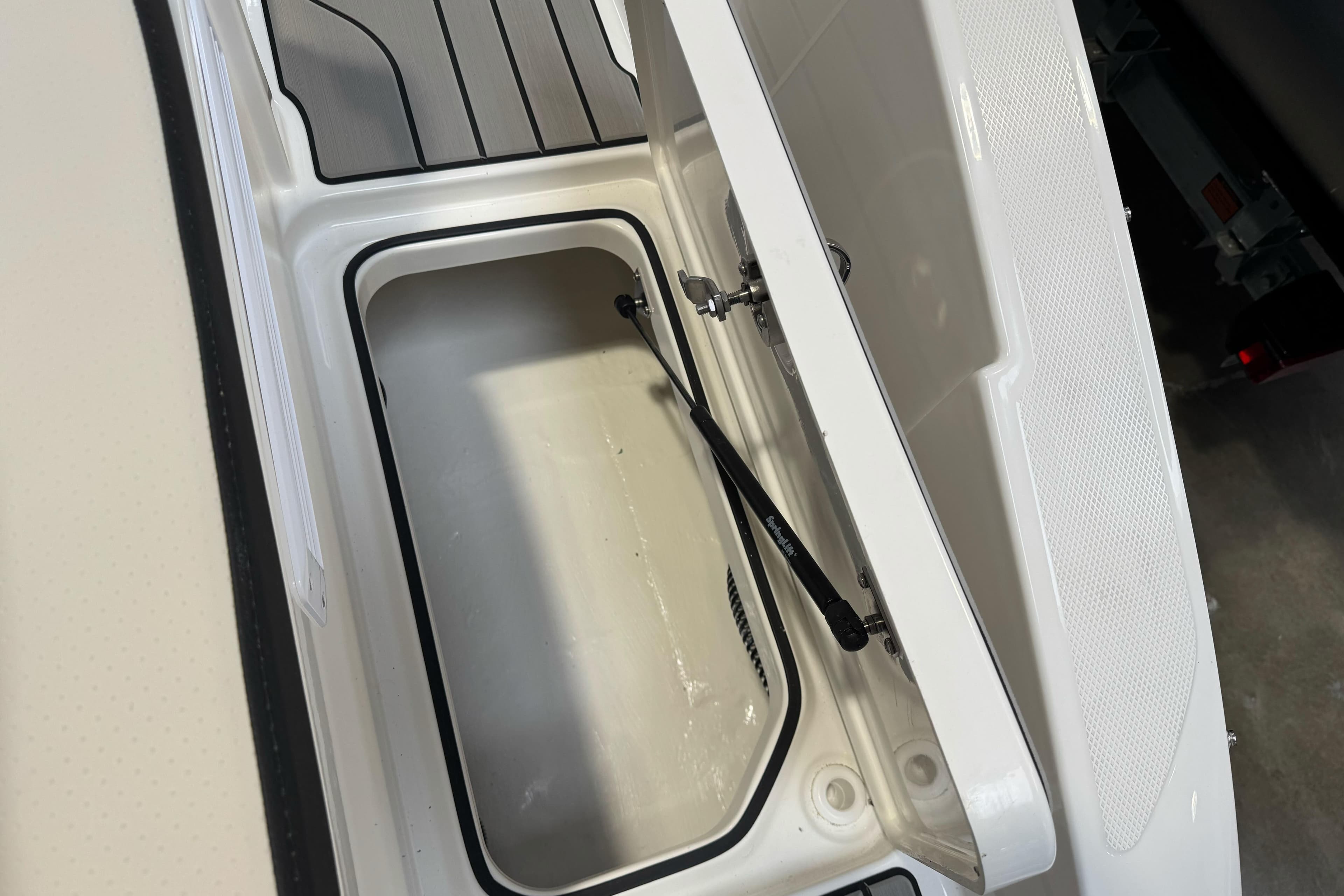 Open storage compartment on 2026 Sea Ray SPX 210 boat, showcasing interior space.