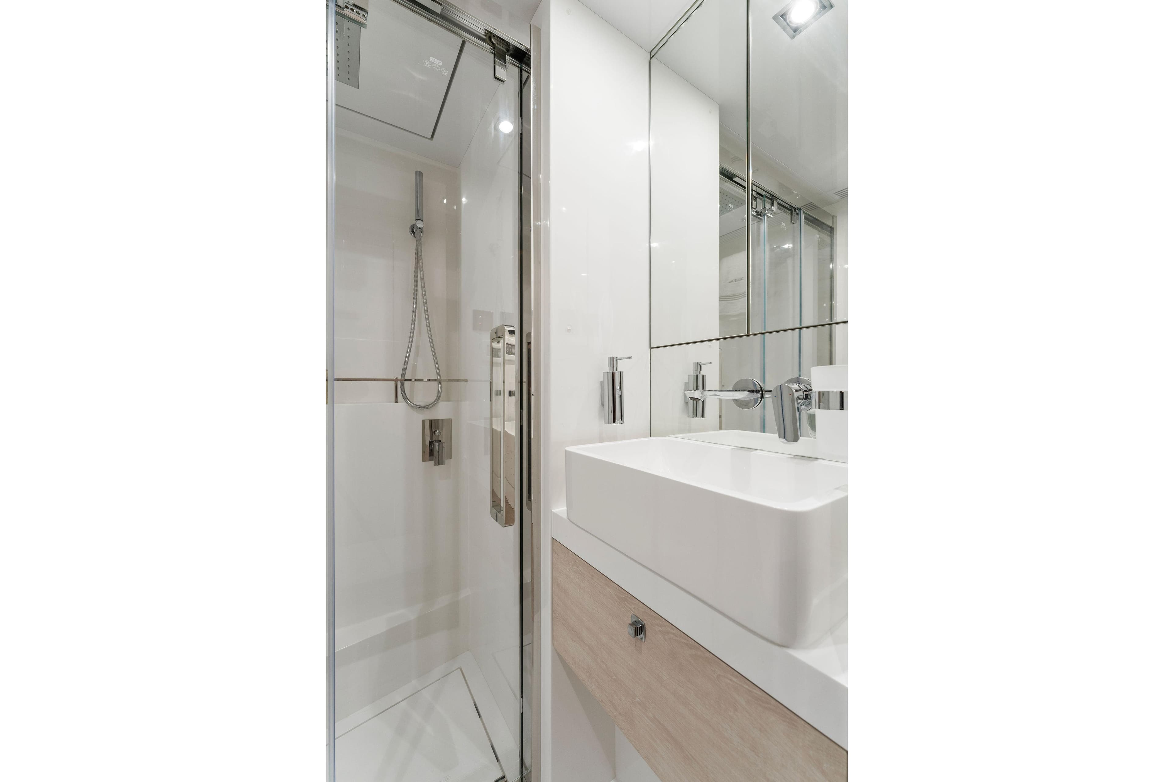 Modern bathroom with glass shower, sleek sink, and mirrored walls in a 2023 Pearl 95 model.