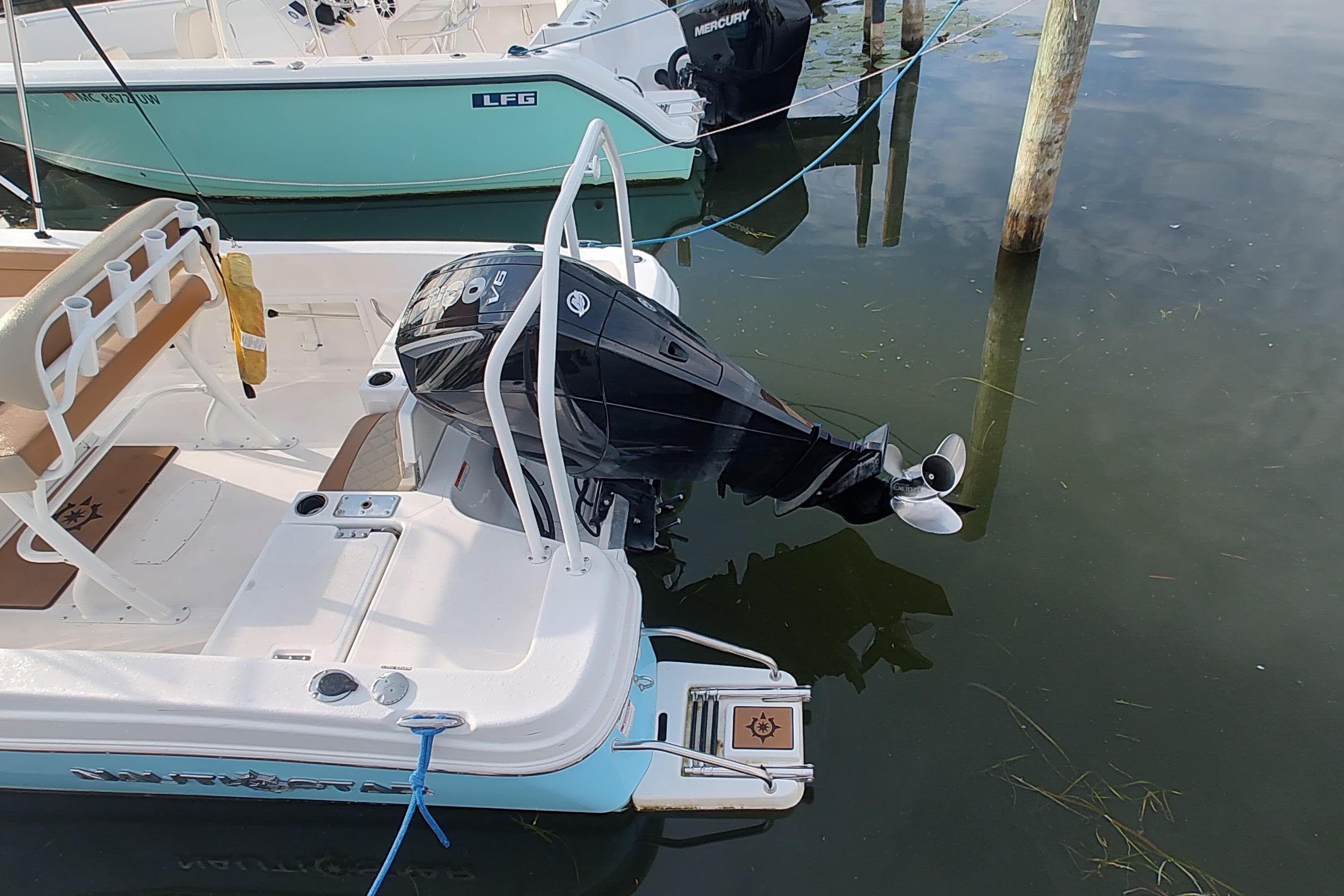 2026 NauticStar 231 Hybrid boat with Mercury outboard motor docked in calm water.