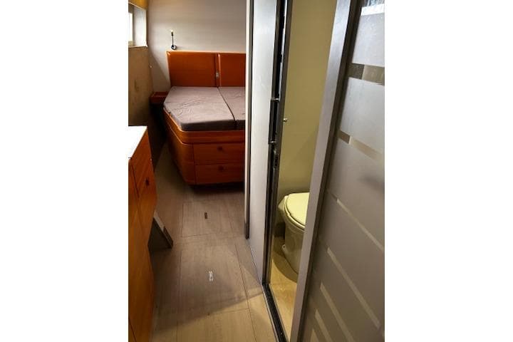 2012 Catana 62 yacht interior with bed and bathroom, featuring modern design and wood accents.